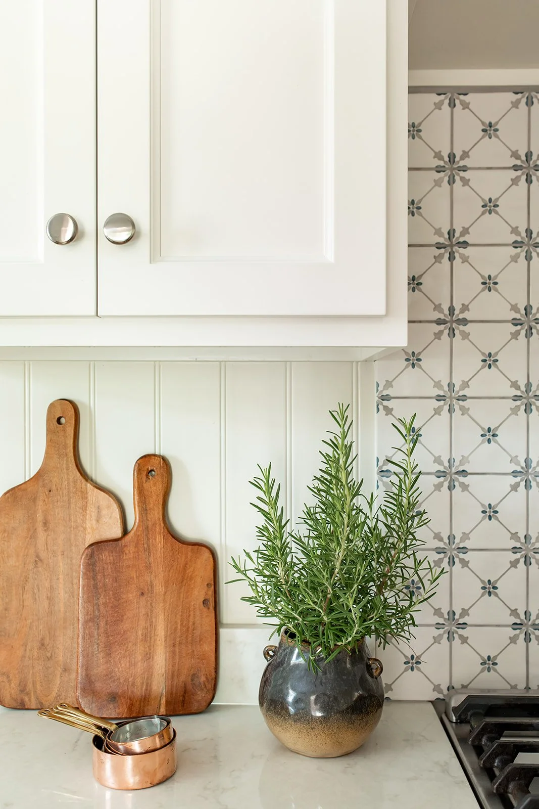 Wood cutting boards and copper against patterned tile and marble-look counters