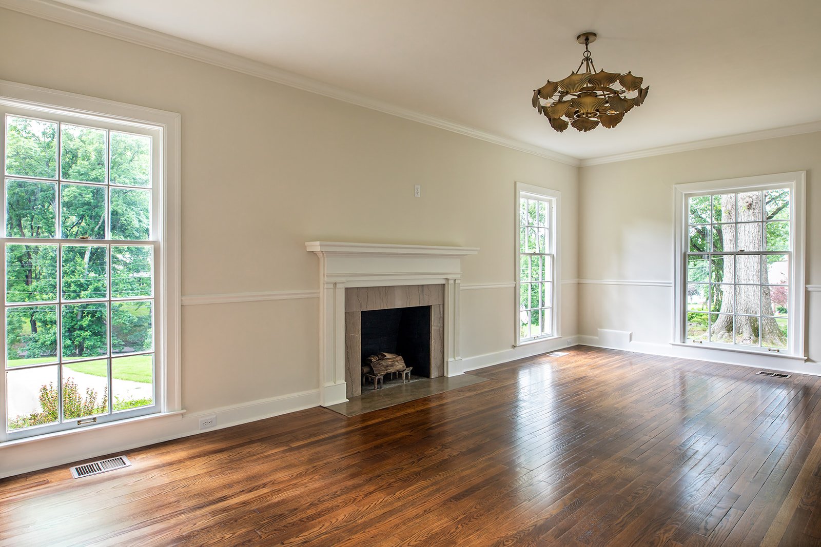 Light-filled living room with a marble-surround fireplace and tall windows