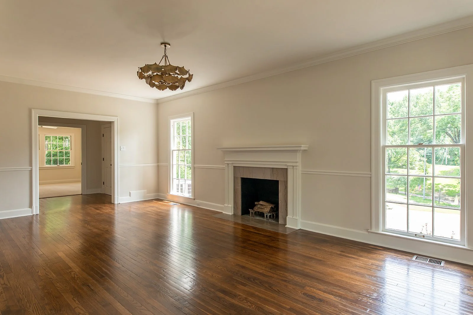 Light-filled living room with a marble-surround fireplace and tall windows