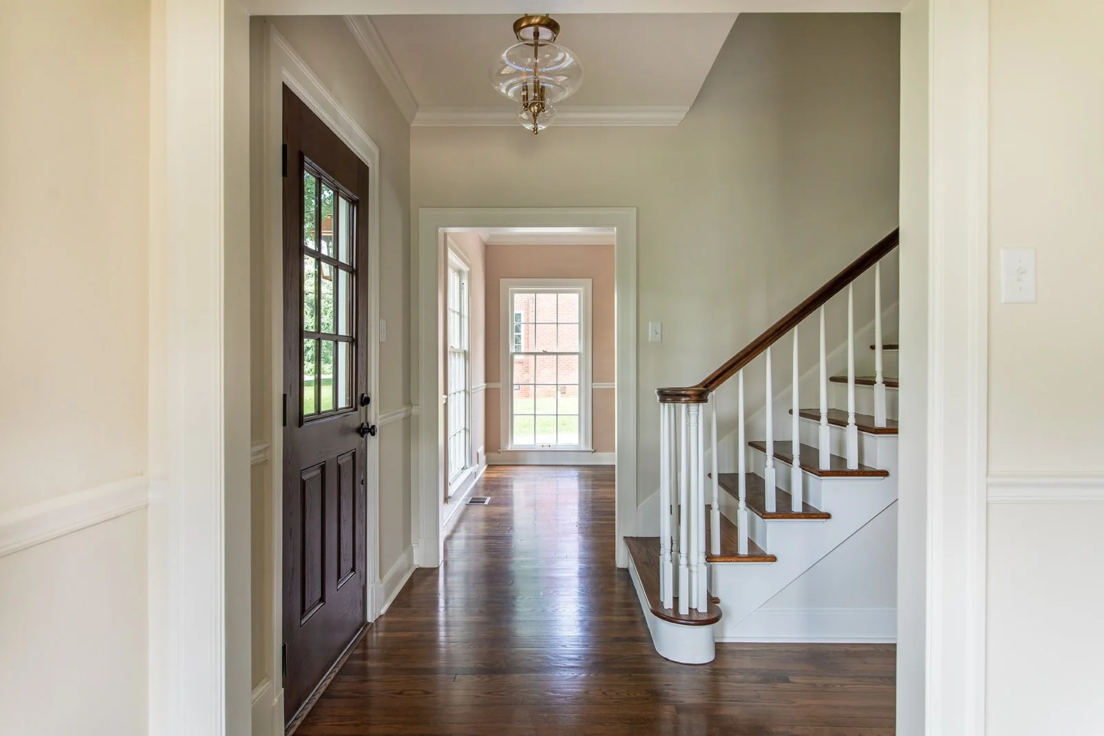 Foyer with a staircase, original dark wood doors, and restored hardwood