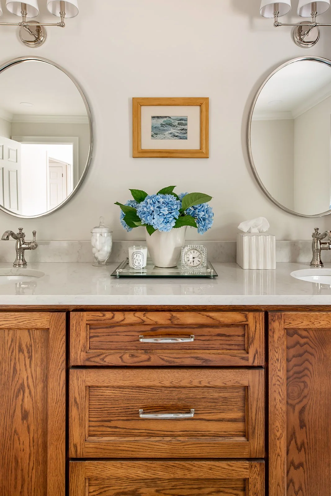 Round mirrors and blue hydrangeas over a wood master-bath vanity