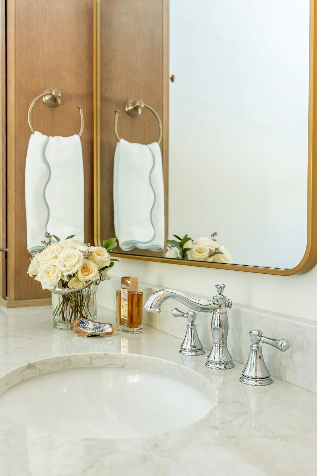 Undermount sink with a polished nickel faucet and roses on a marble vanity