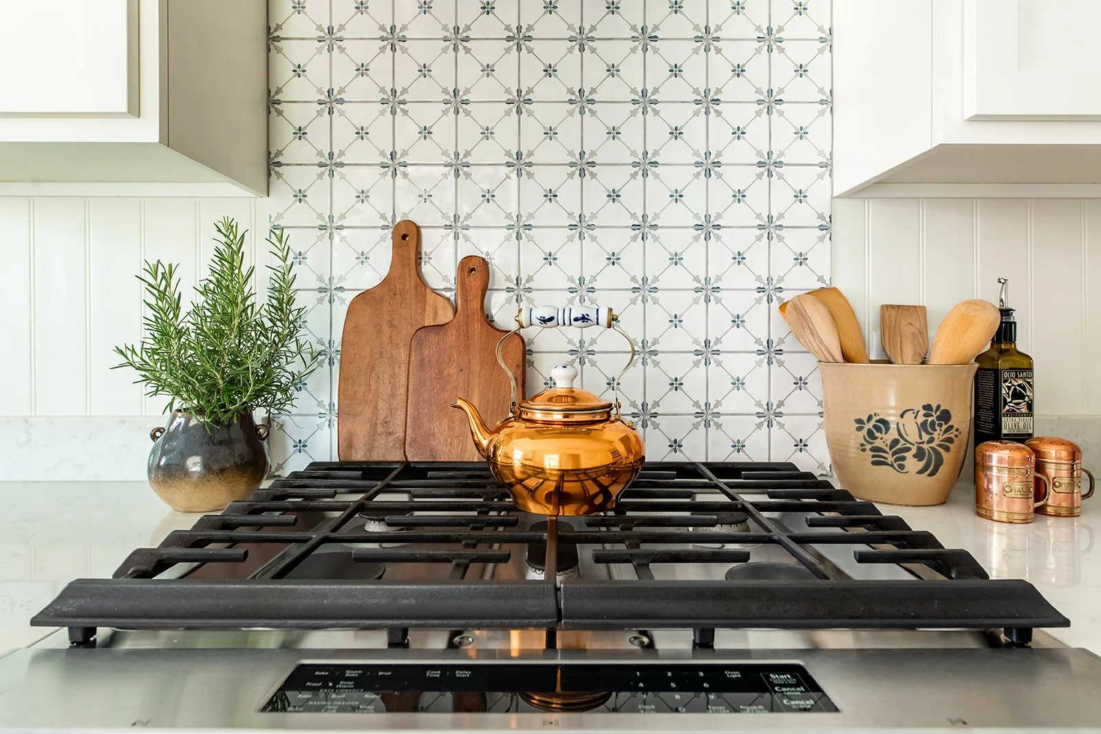 Cooktop styled with a copper kettle and wood boards against patterned tile
