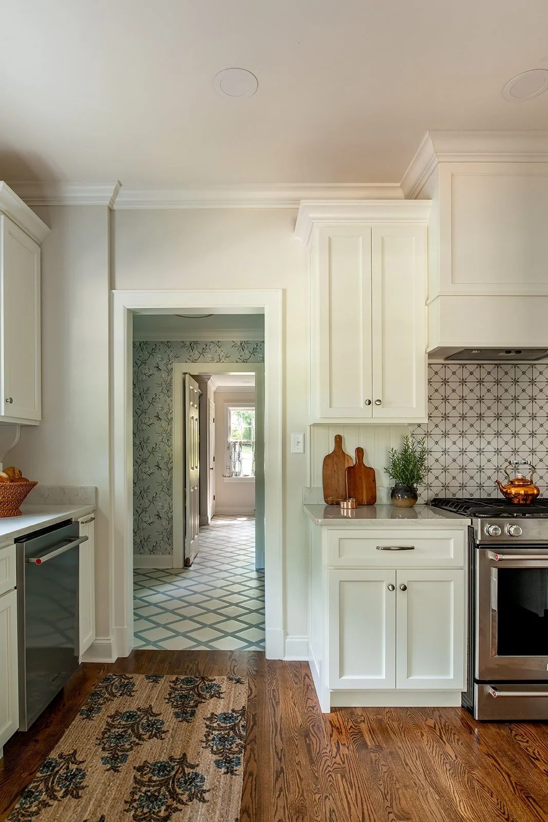 Kitchen doorway opening to a chinoiserie wallpaper hall with a painted lattice floor