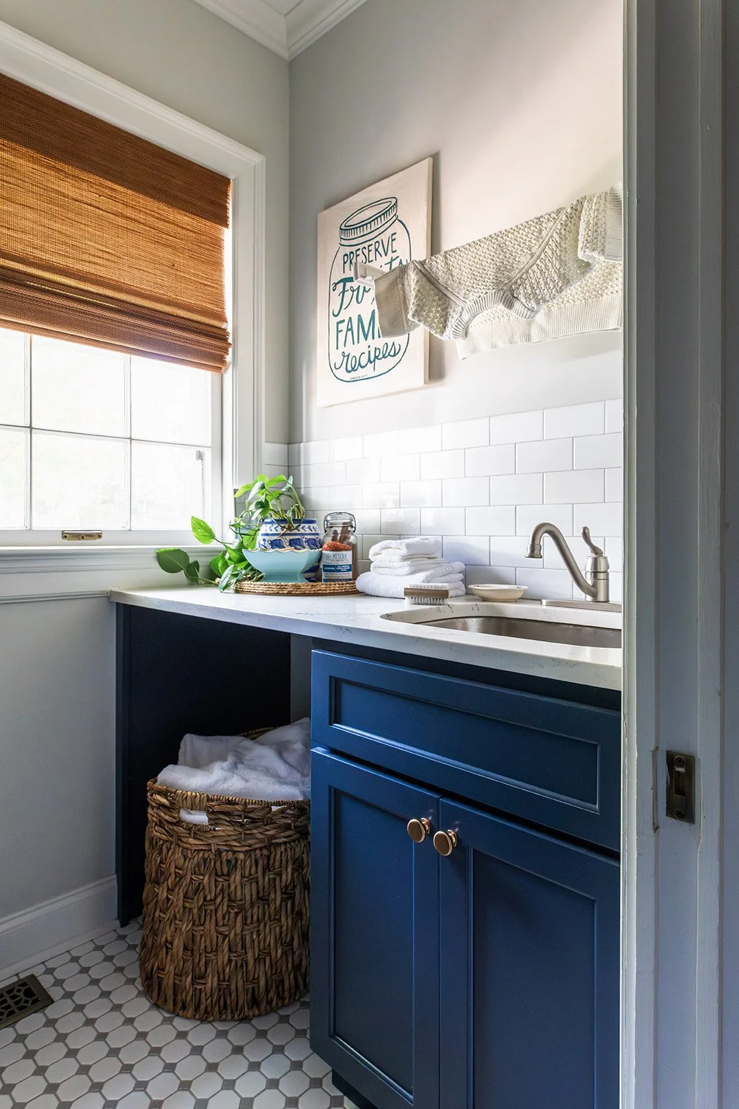 Laundry room with a navy cabinets, sink, and woven basket over patterned tile