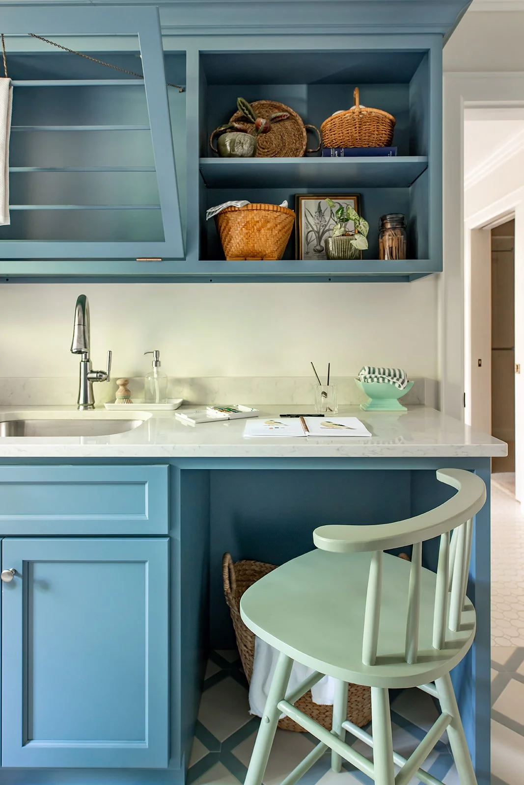 Open shelves with baskets and a green stool in the blue laundry room