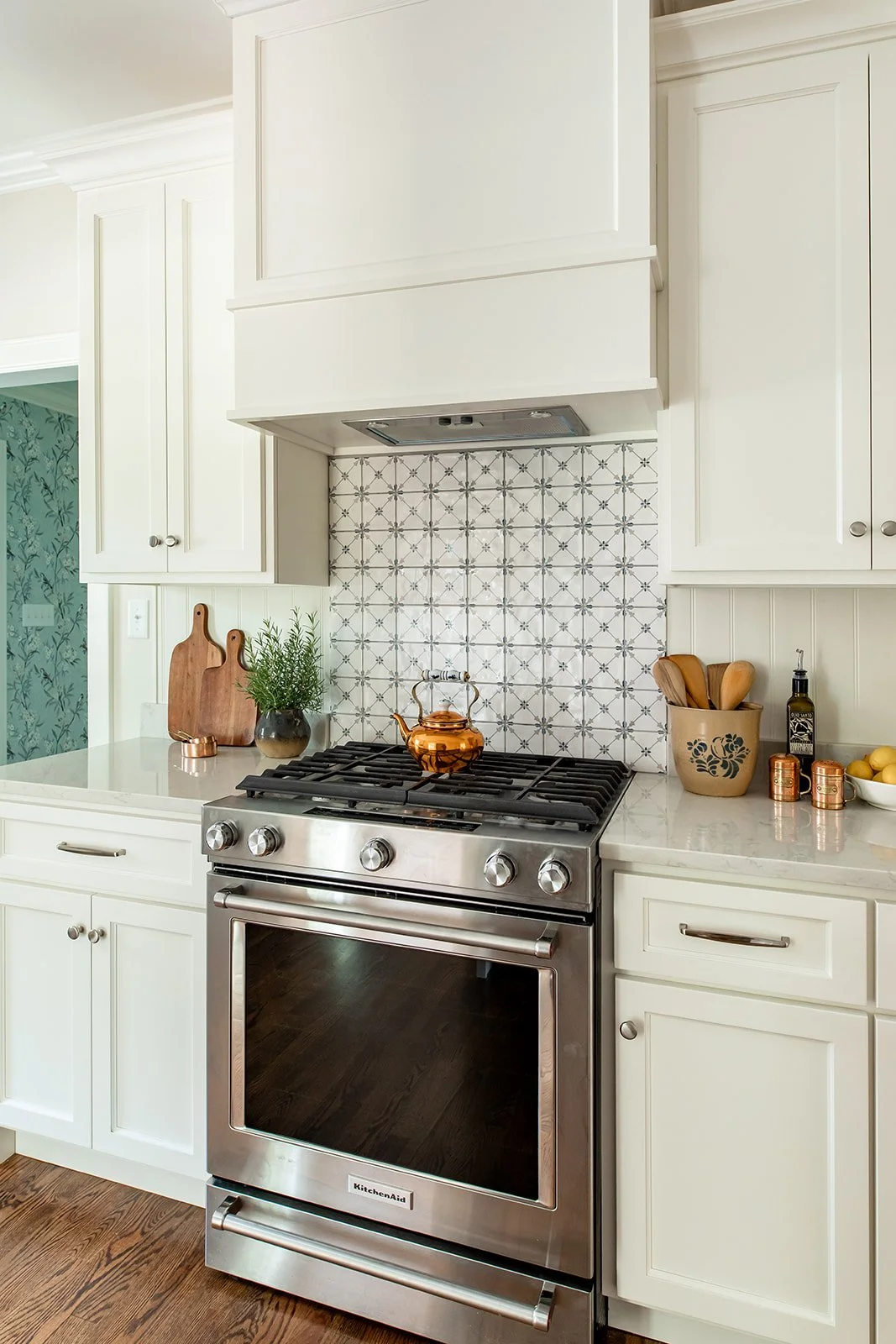 Custom vent hood and patterned tile with a glimpse of the blue wallpaper hall