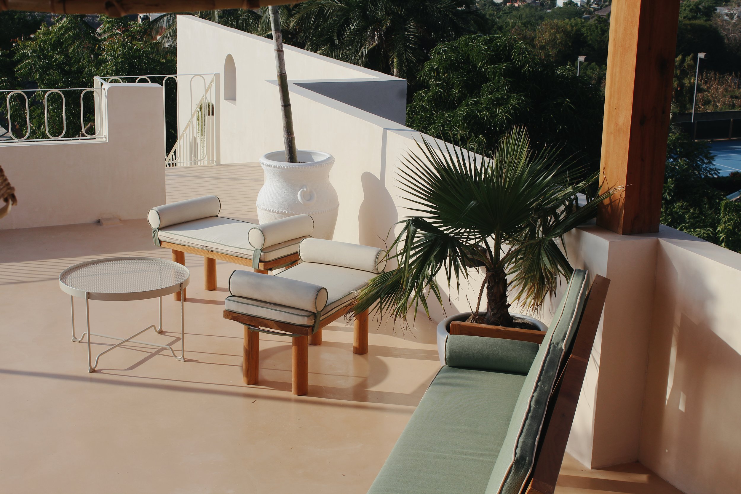 Terrace with modern outdoor seating and table, potted palm tree, and cream-colored walls.