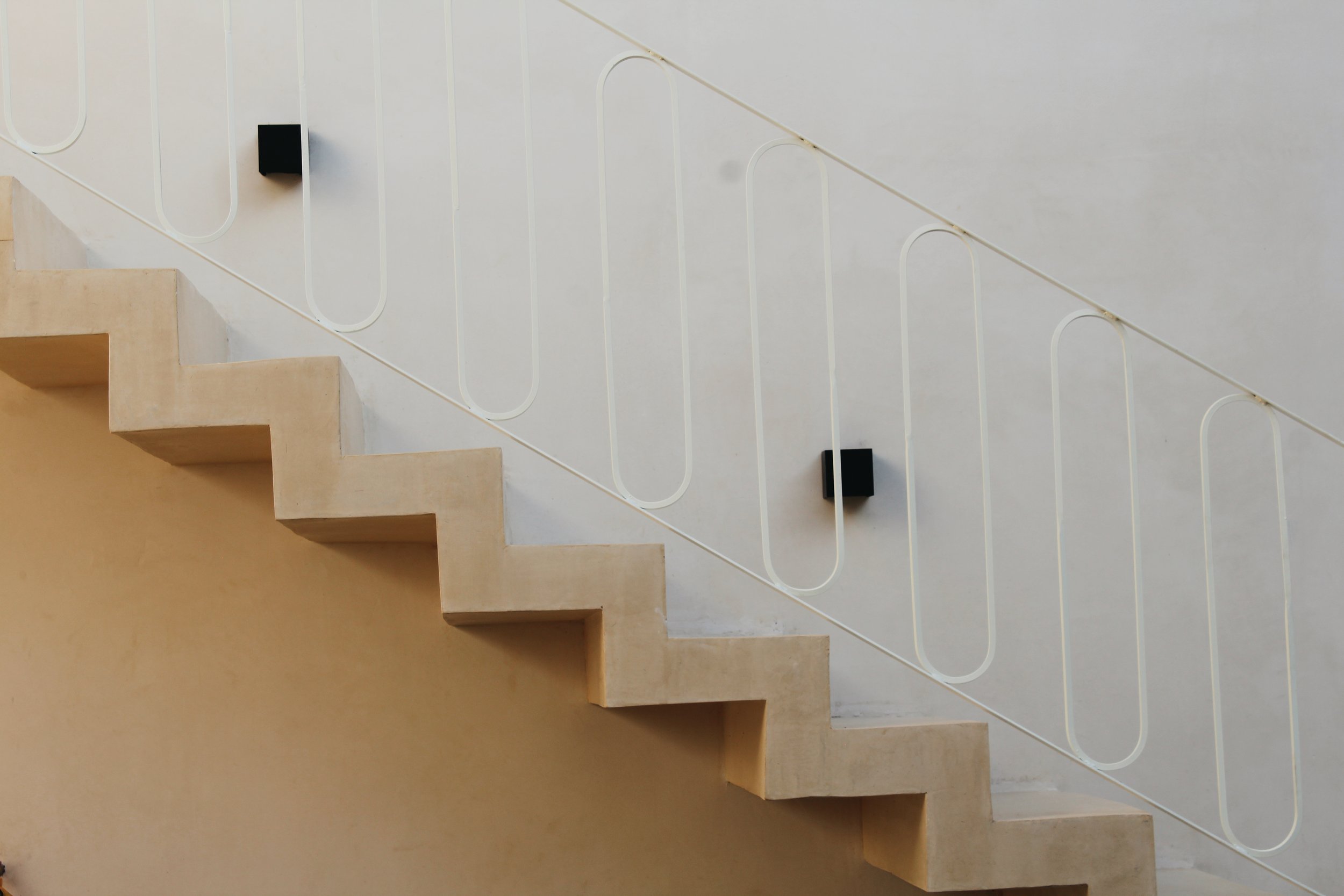 Minimalist staircase with geometric railing and beige walls.