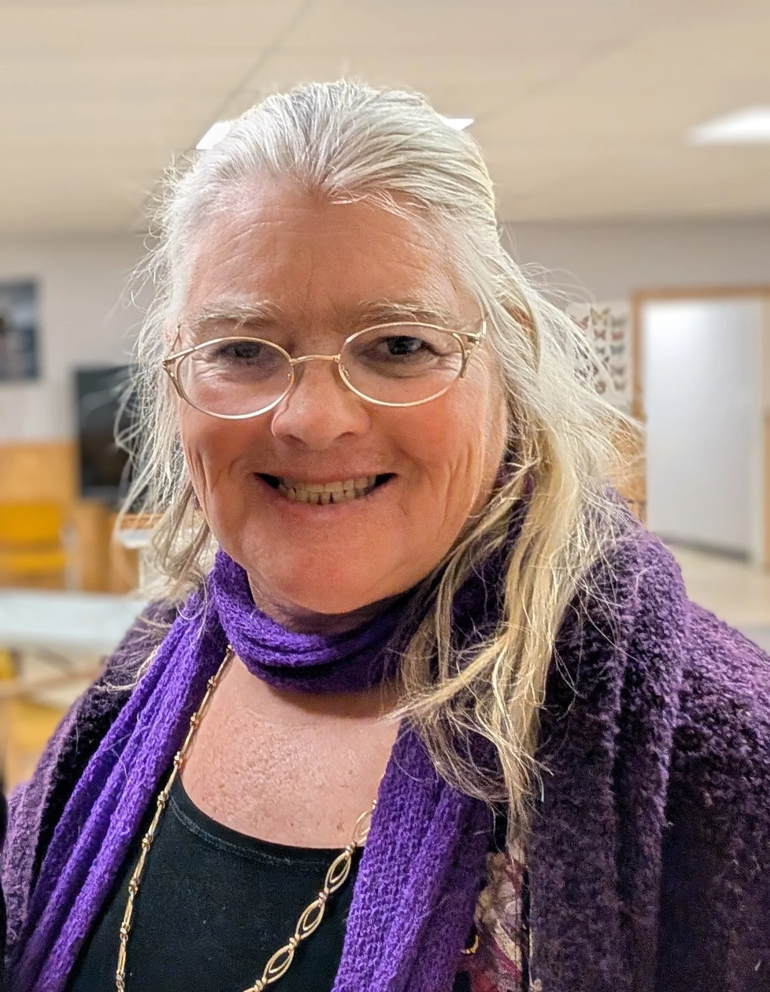 Melinda Myers smiles at the camara, she is wearing wire rimmed glasses and a purple scarf.