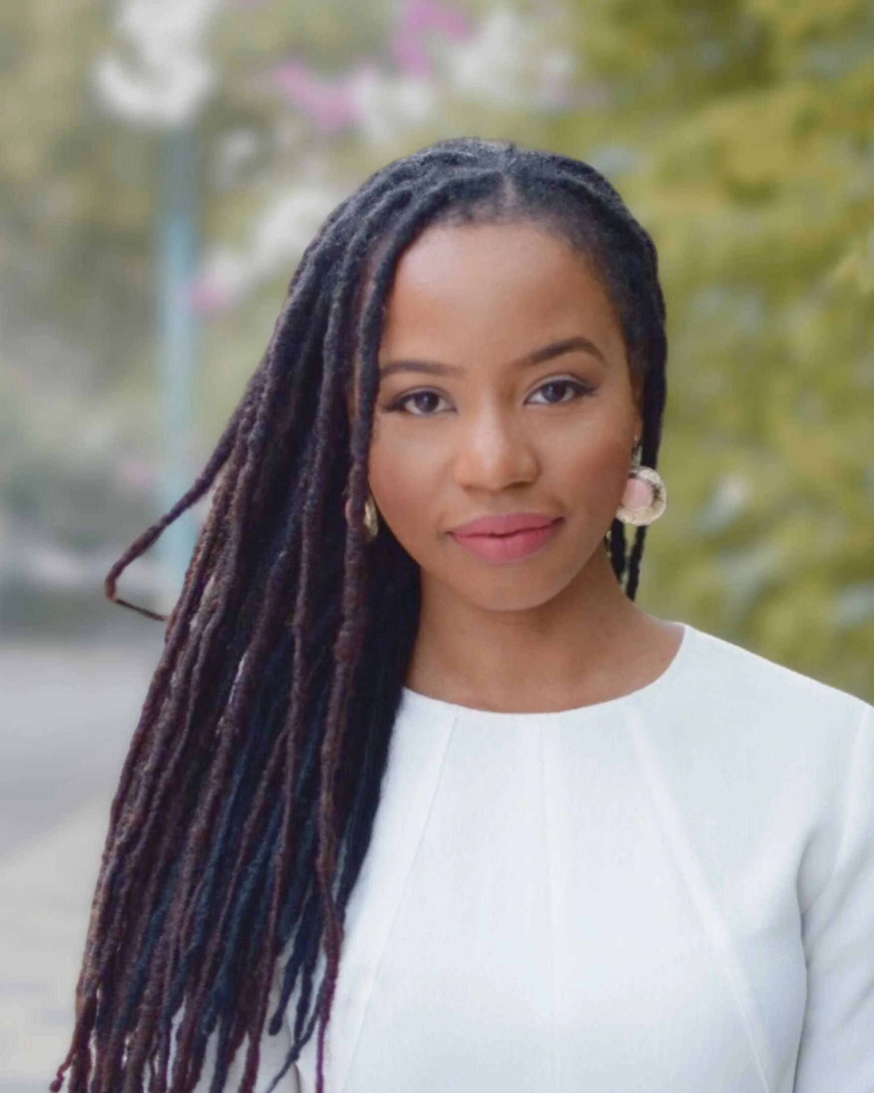 Owner of Neourish Brand Marketing studio standing confidently outdoors, wearing professional white attire and smiling warmly.