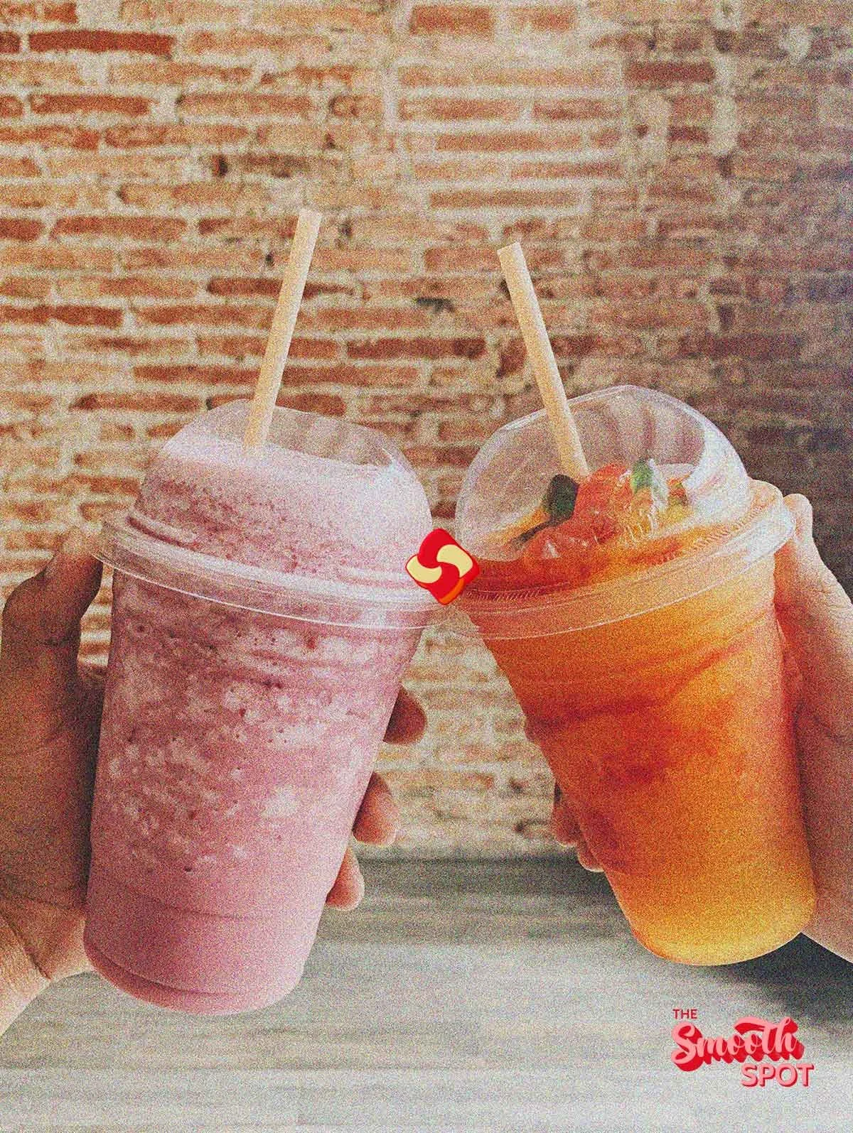 Two hands cheersing each other with a smoothie in each hand, creating a lively and refreshing moment, emphasizing the vibrant colors of the drinks.