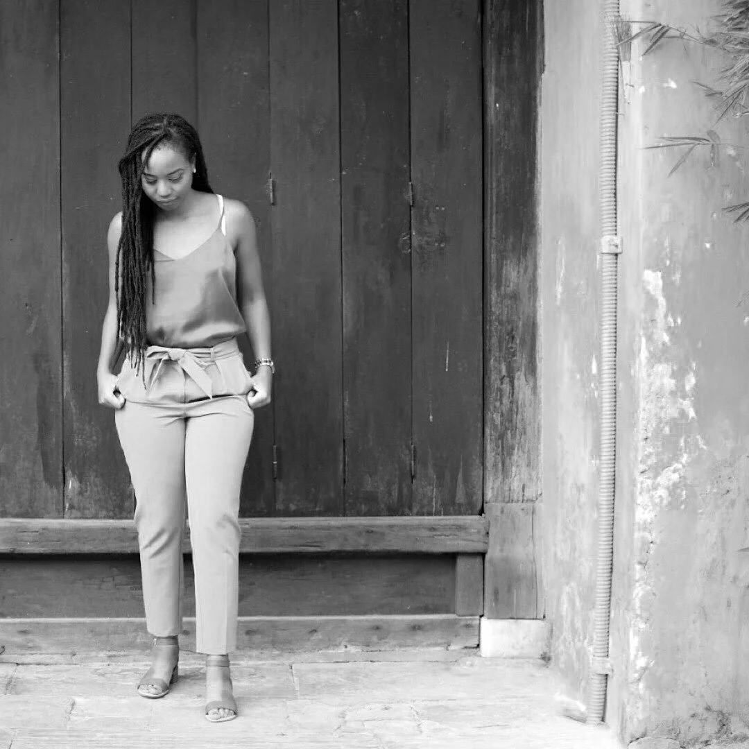 Black and White image of owner of Neourish Brand Marketing studio standing confidently outdoors, wearing professional attire and looking down.