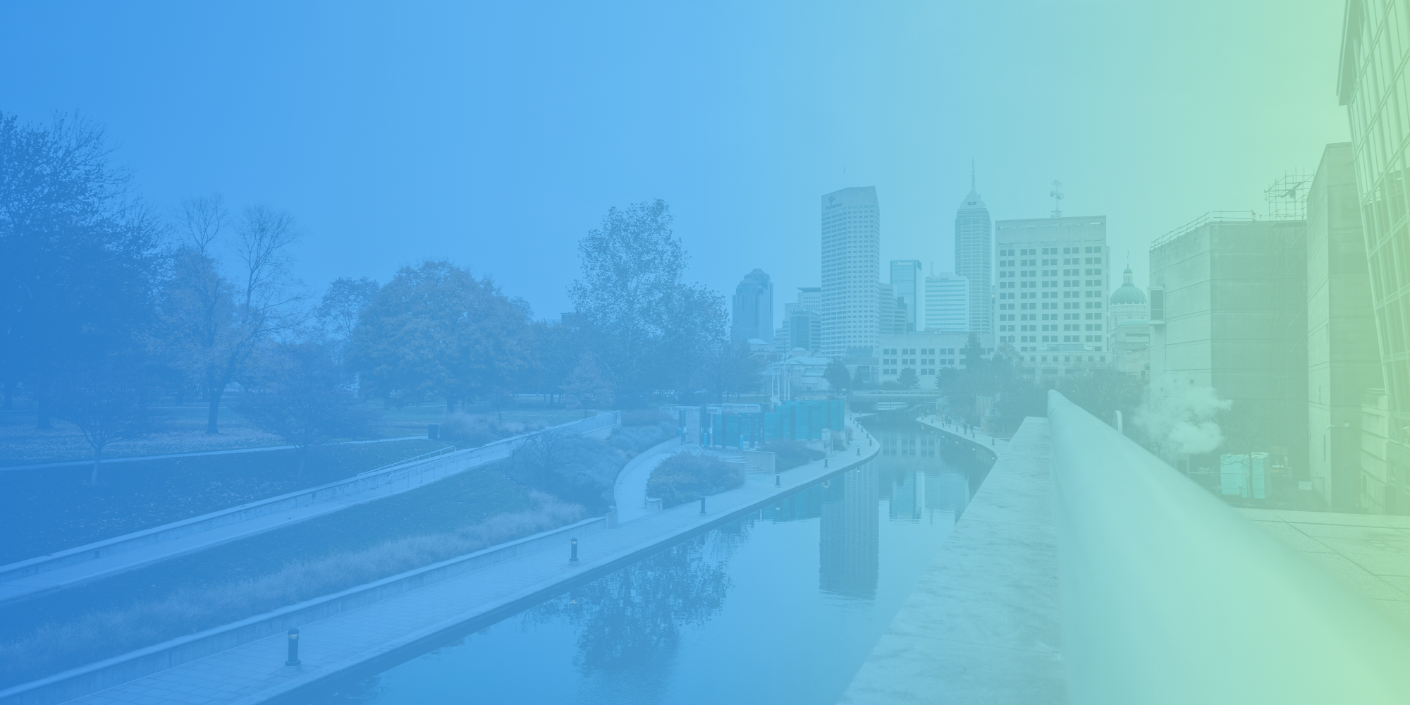 City skyline with tall skyscrapers and a river in the foreground, overlaid with a gradient from blue to green.