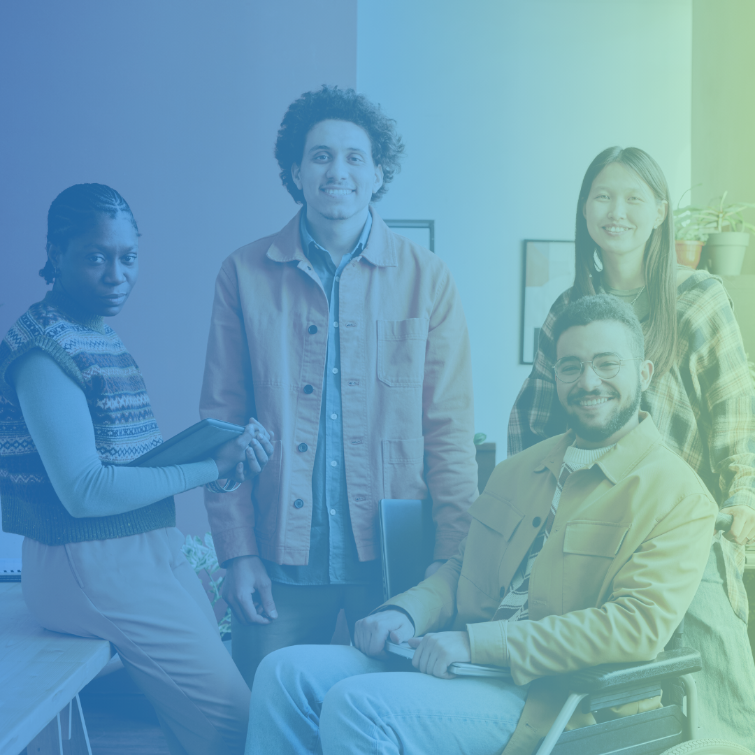 Group of five diverse young adults in a casual office setting, smiling and posing for the camera.