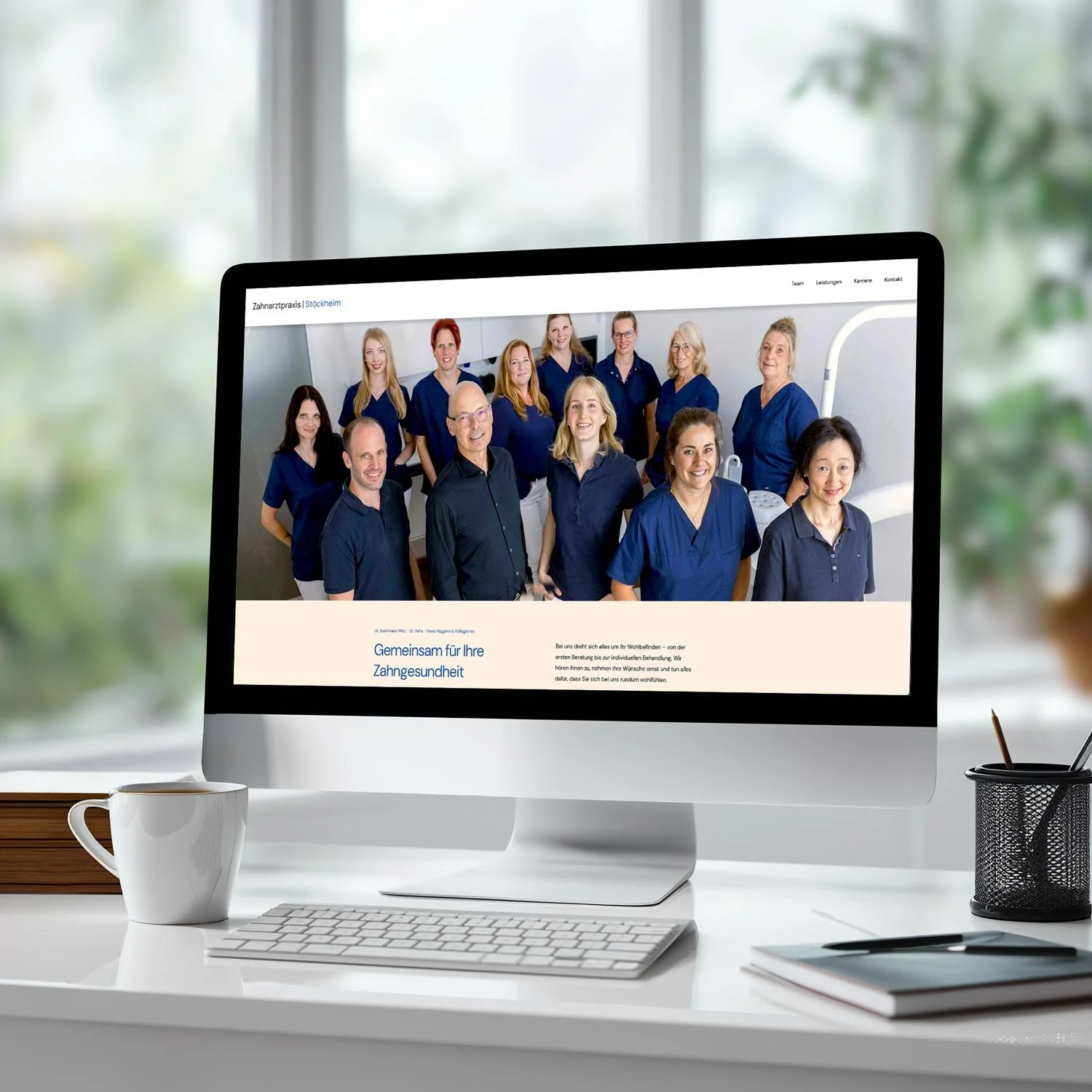 Computerbildschirm mit einem Gruppenfoto von medizinischen Fachkräften in blauen Uniformen, darunter Männer und Frauen, vor einem weißen Hintergrund.
