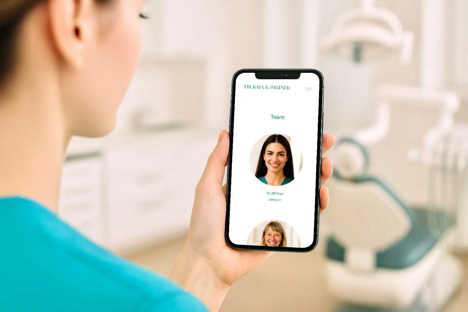 Eine Zahnärztin hält ein Smartphone, auf dem die Teamseite einer Zahnarztpraxis mit Fotos der Zahnärztinnen Dr. Elif Kaya und einer weiteren Ärztin zu sehen ist.