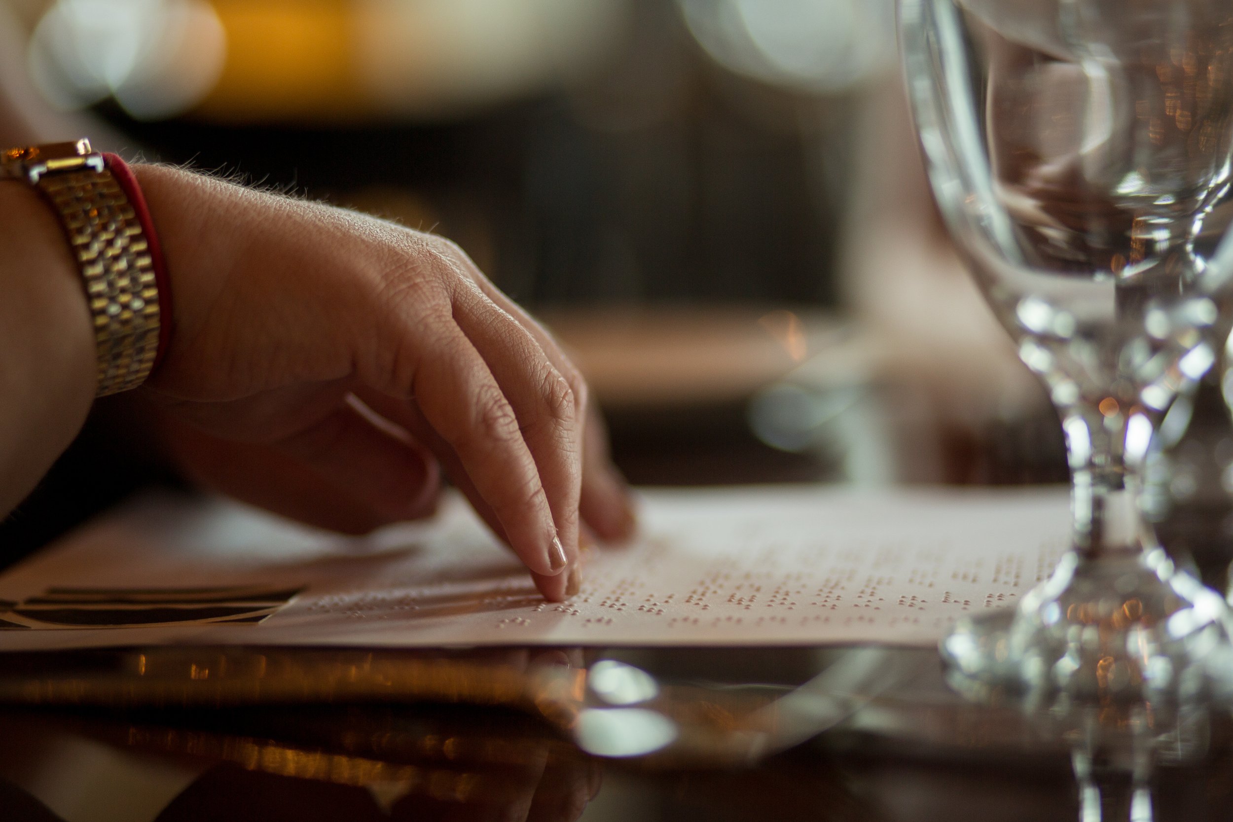 Woman reads a braille menu in a nice restaurant