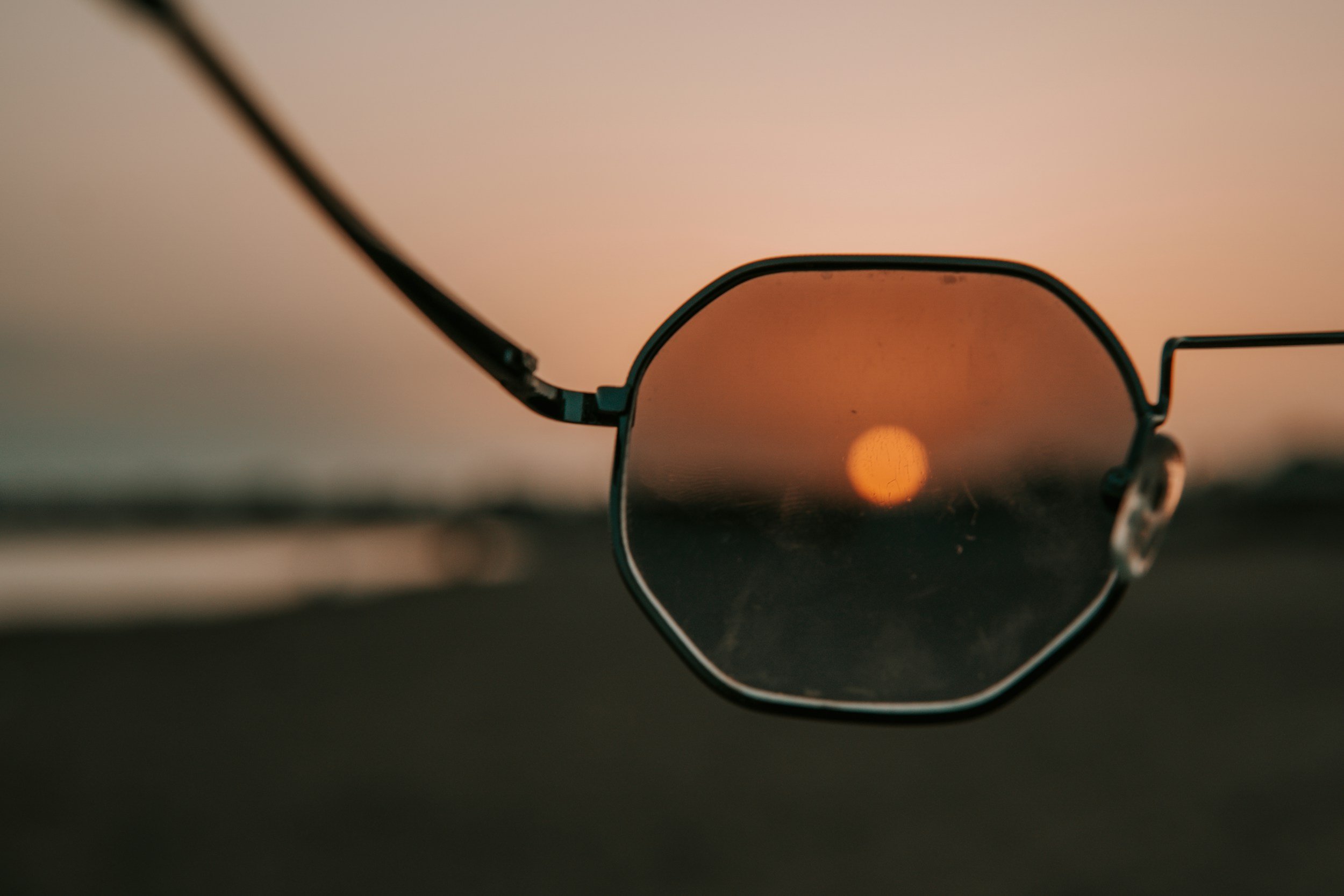 Sunglasses with an orange sunset reflected in the lens, a symbol for brainspotting