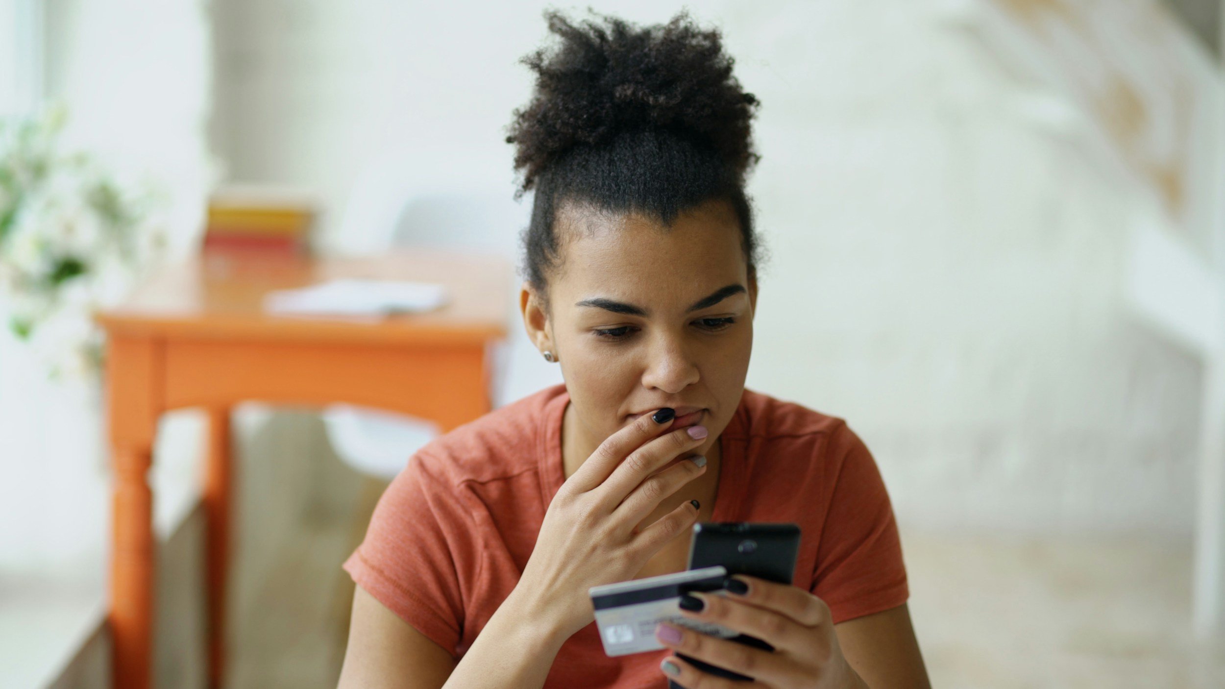 A person looks at their phone while holding a credit card.