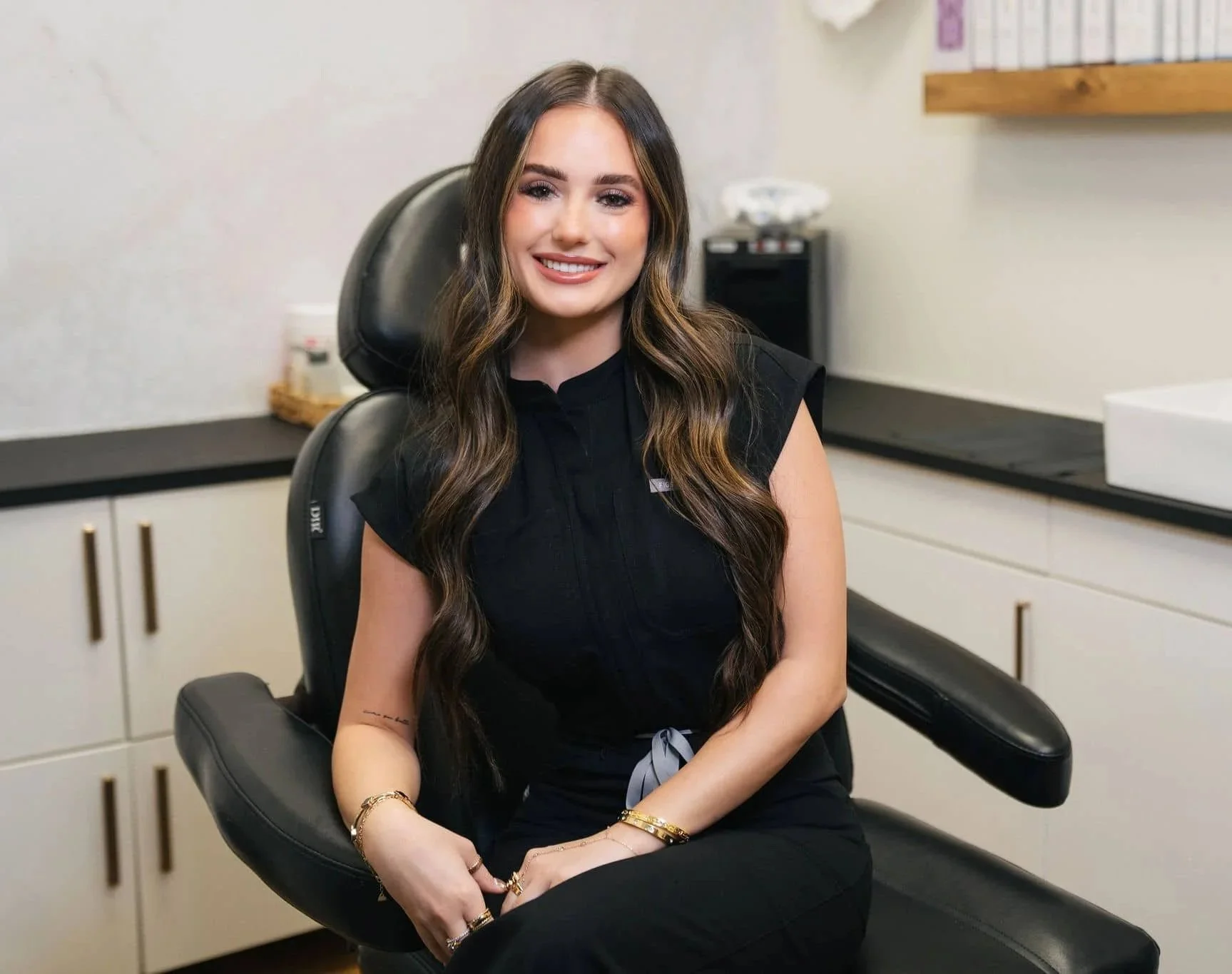 Hailey Holtorf sitting in a black leather salon chair while smiling at the camera.
