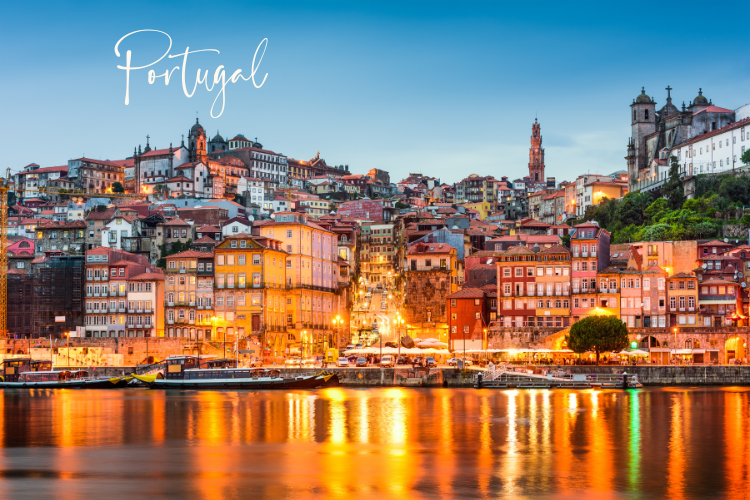 Scenic view of Porto, Portugal at twilight, showcasing colorful buildings along the Douro River, with reflections on the water and historic architecture in the background.