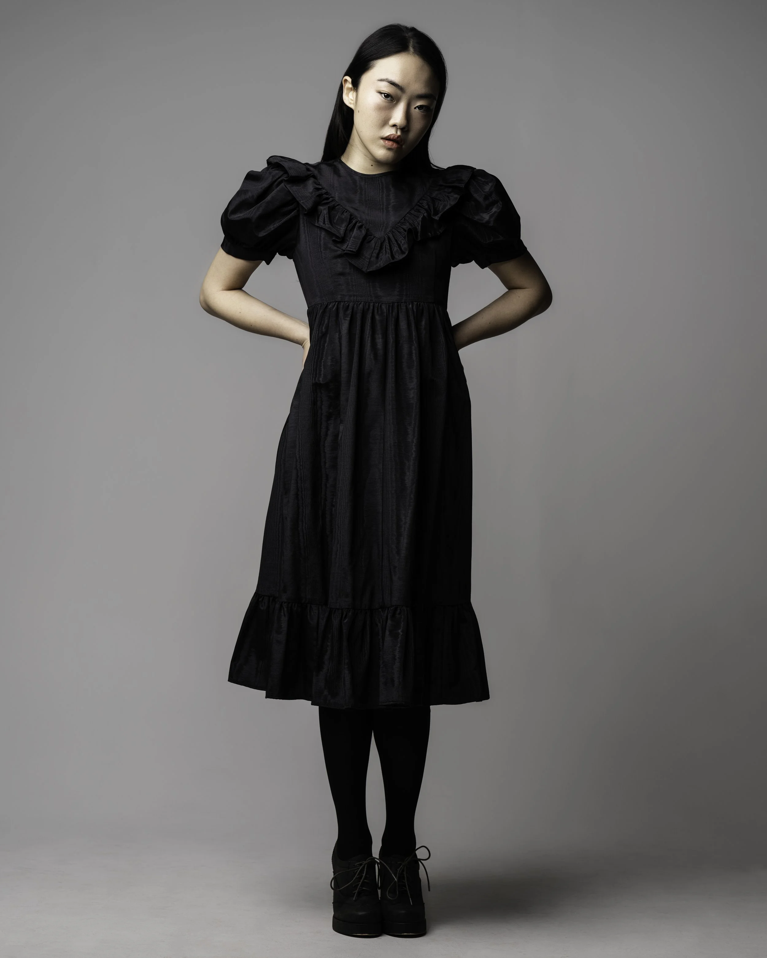 light grey background with model in a black dress