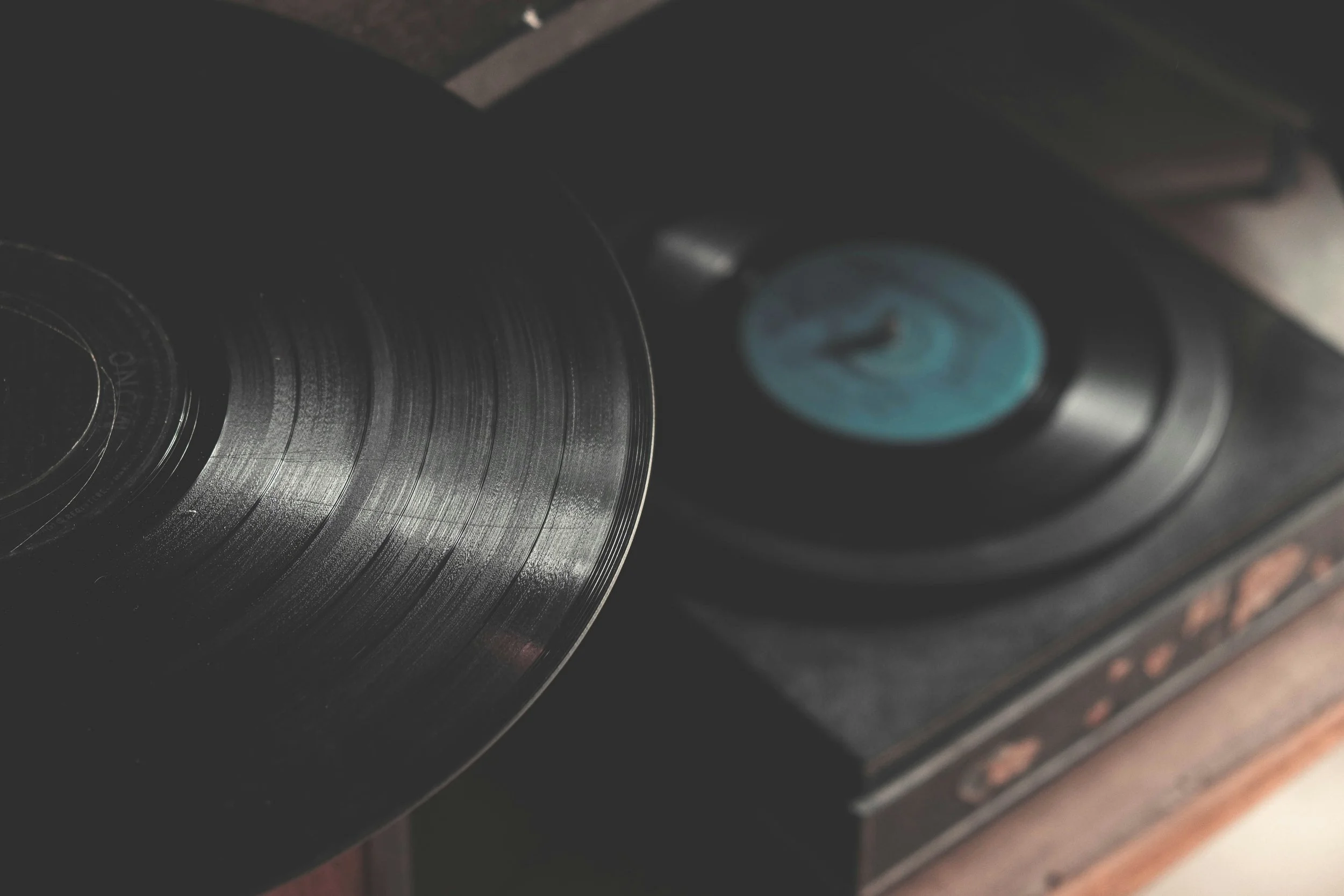 Close-up of a vinyl record on a turntable, with one spinning and another resting in the background.