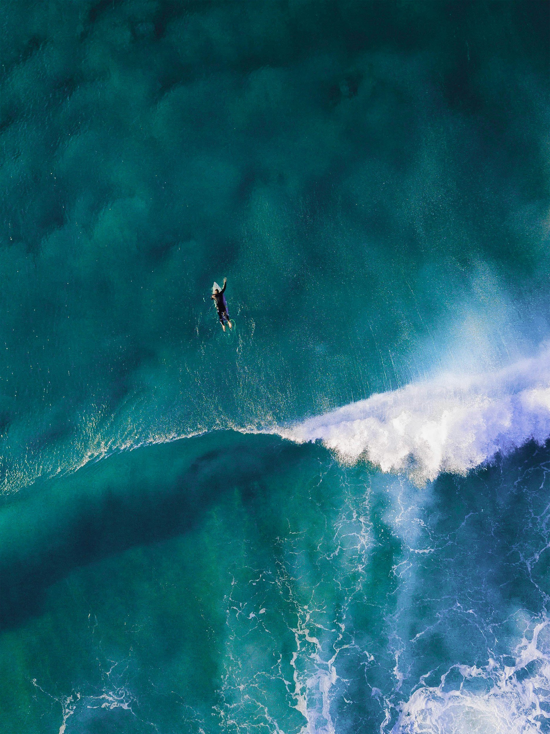 Surfer paddling out at a Northern Beaches break with lower back extended