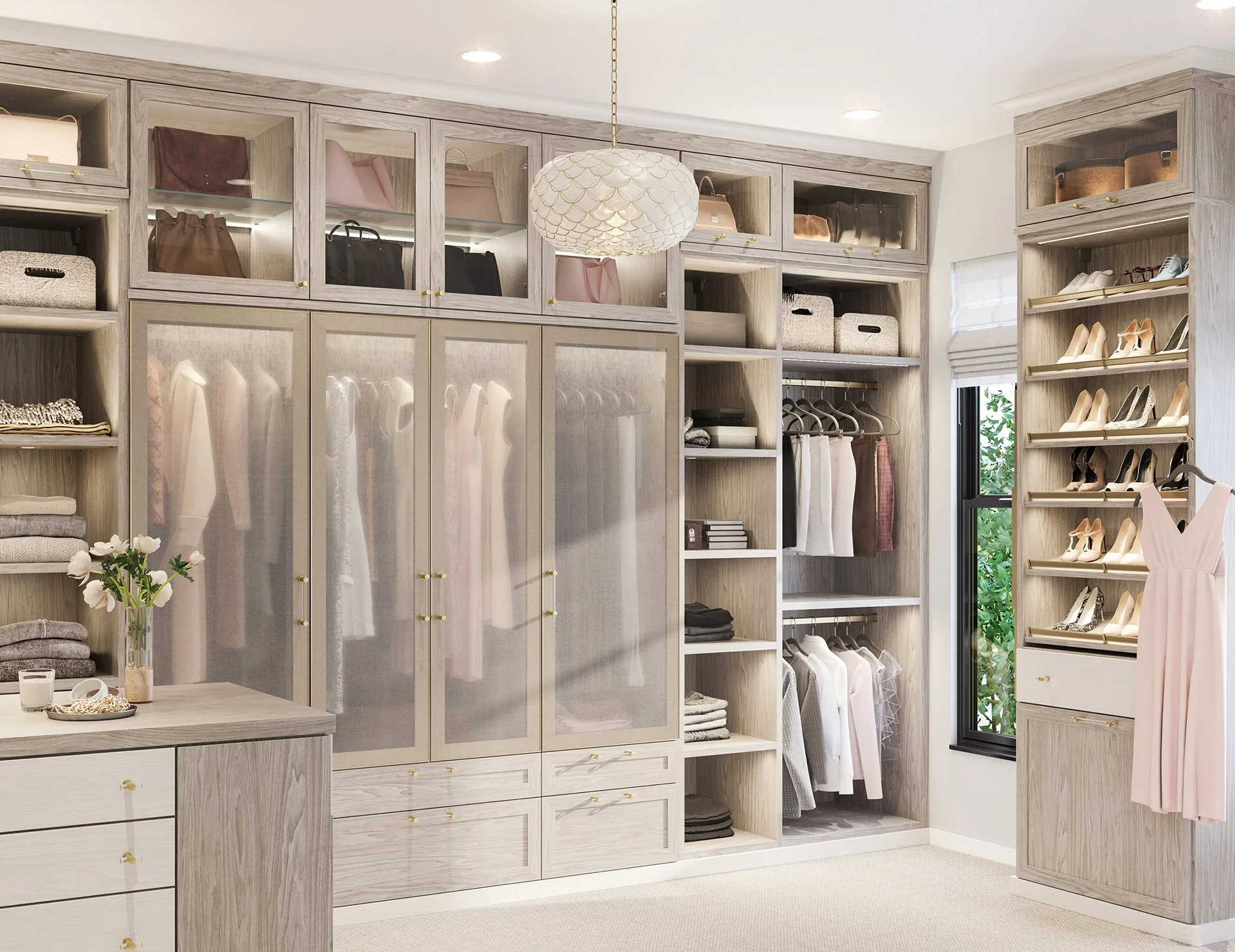 A walk-in closet with light wood cabinetry and shelving, featuring hanging clothes, shoes, and storage boxes, illuminated by ceiling lights and a window with a view of greenery.