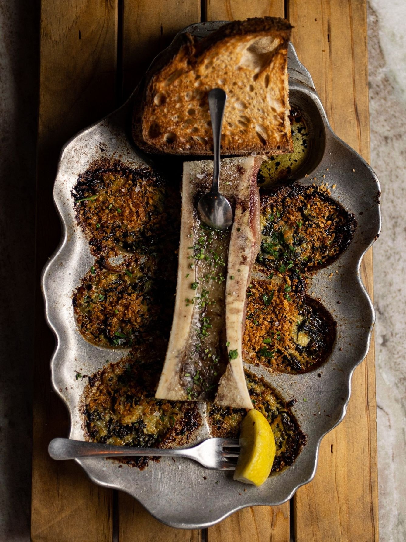 The move is to build the bite. Roasted oysters with Pernod, kale, lemon, gruyere, and breadcrumb, served alongside bone marrow and sourdough.