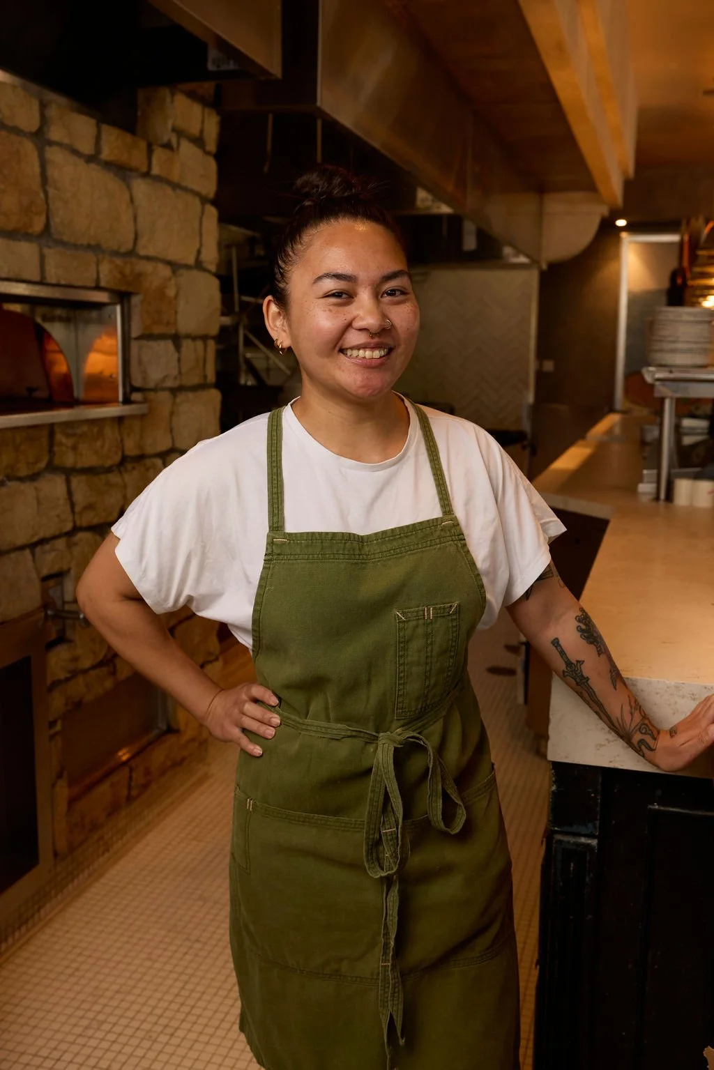 Chef de Cuisine Chianne Mallari slicing meat in front of the wood-fired oven at Herb & Sea, Encinitas