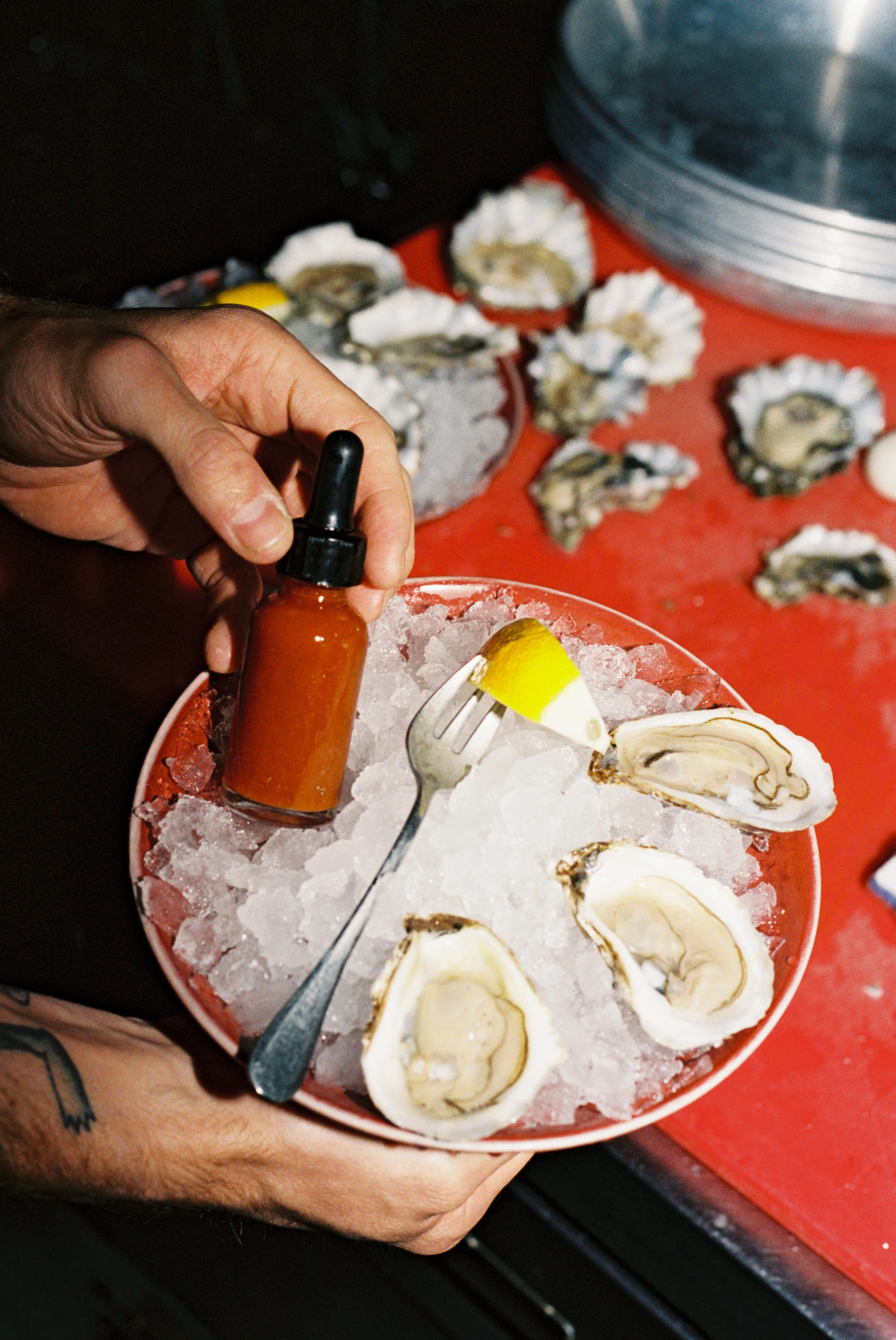 Three oysters on a bed of ice with a lemon wedge and house hot sauce