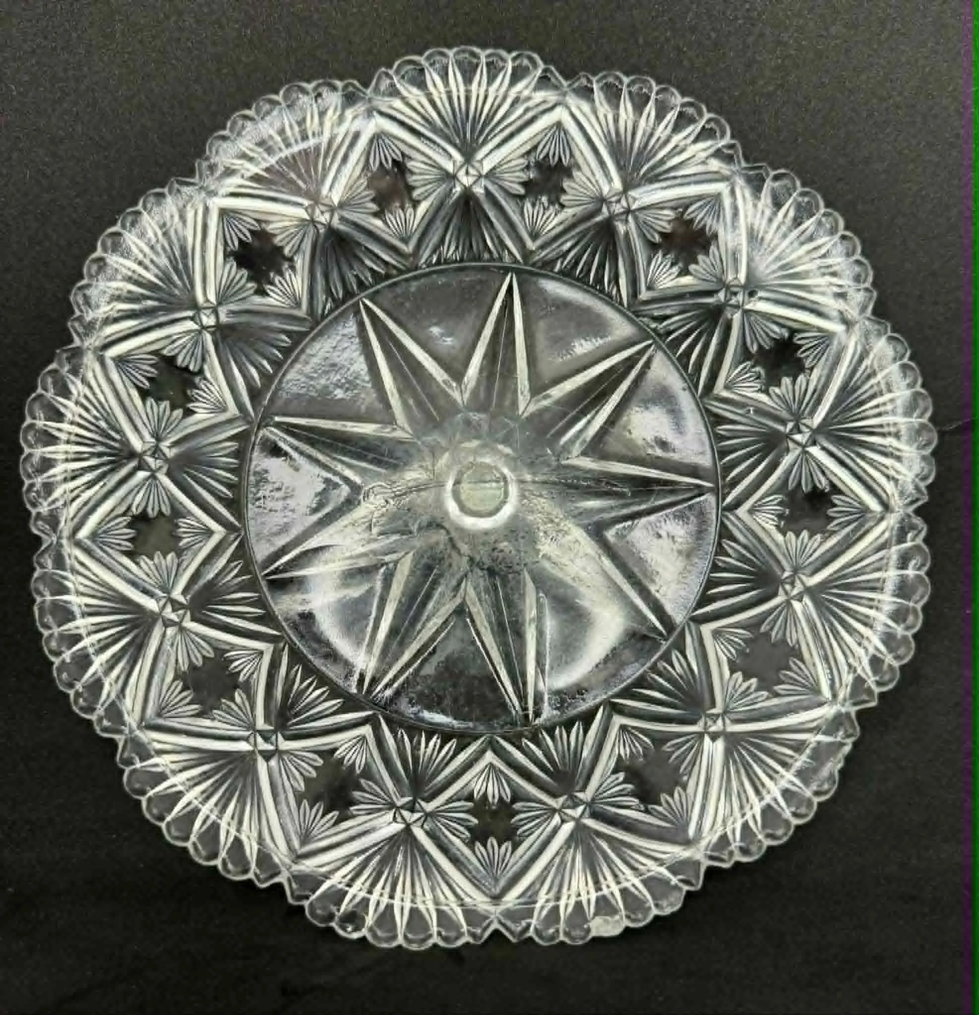 Close-up of an intricate clear glass bowl with detailed patterns on a black surface.