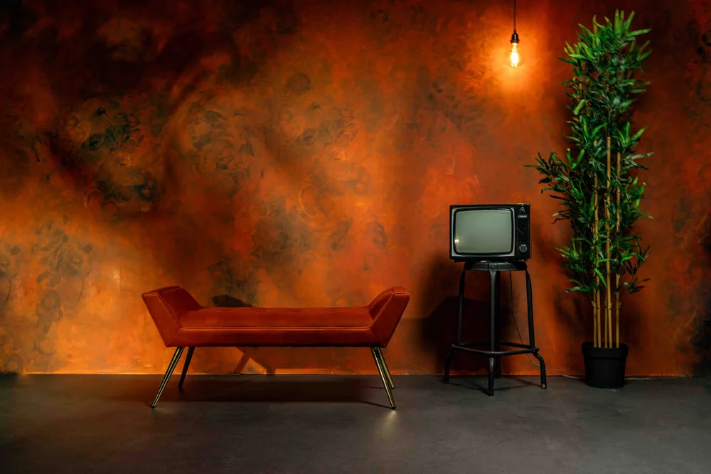 Warm textured set with a red bench and vintage TV