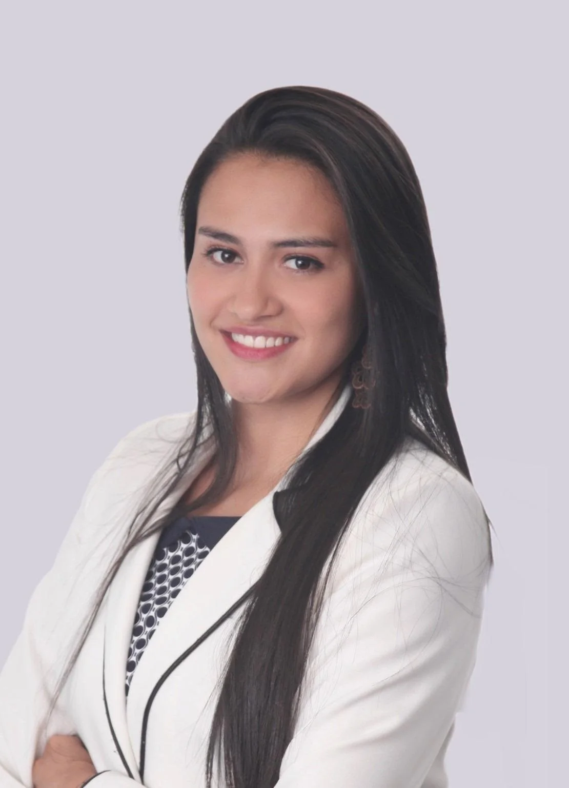 Professional woman with long dark hair, wearing a white blazer and black and white top, smiling at the camera against a plain light background.