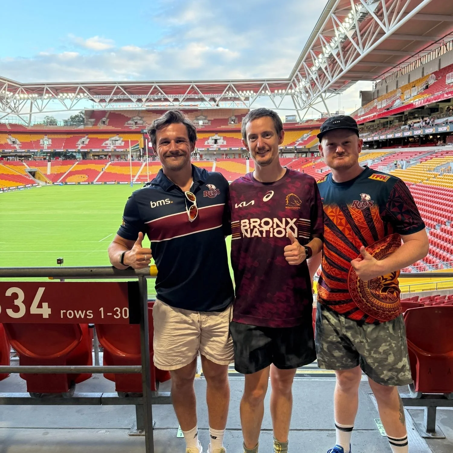 Two NDIS participants posing for a picture together with their support worker in a stadium