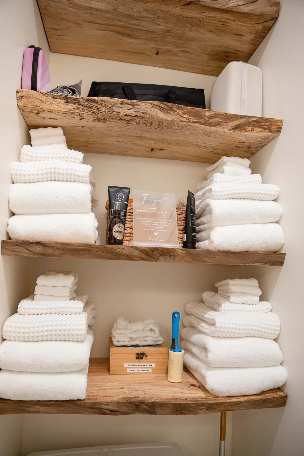 Luxurious bathroom shelf with neatly folded white towels, personal care items, and a cleaning brush.