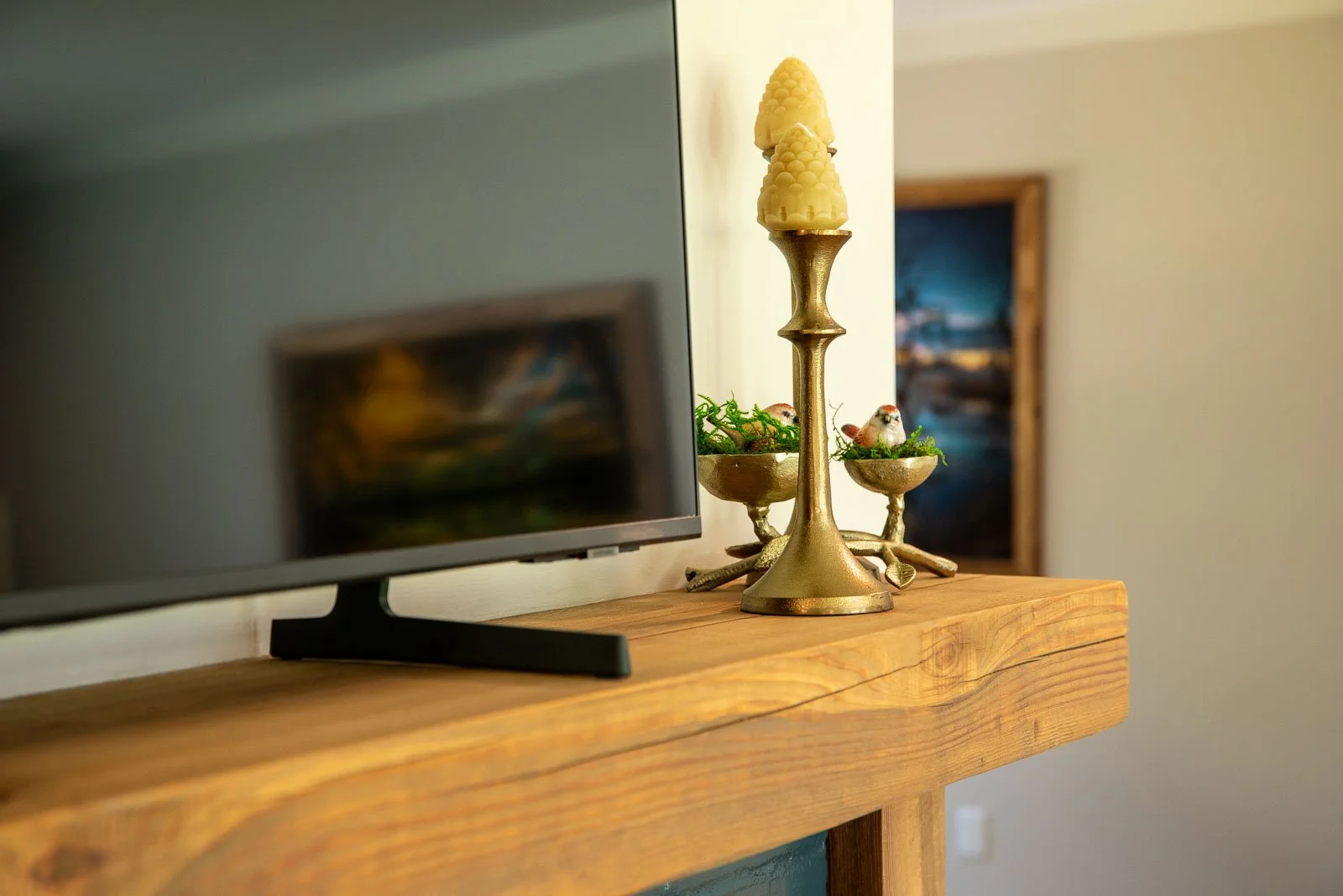 Decorative candle holder with three candles and small birds on a wooden surface.