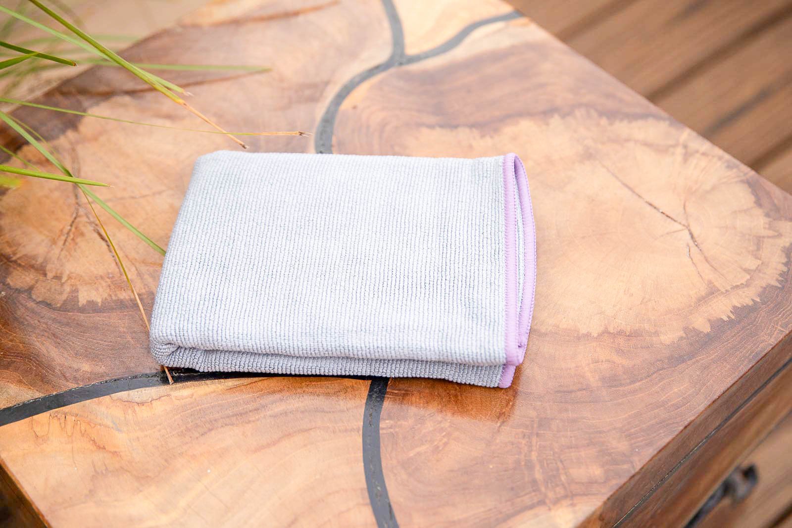 A folded white cloth with a pink edge placed on a wooden surface with natural patterns and a crack.