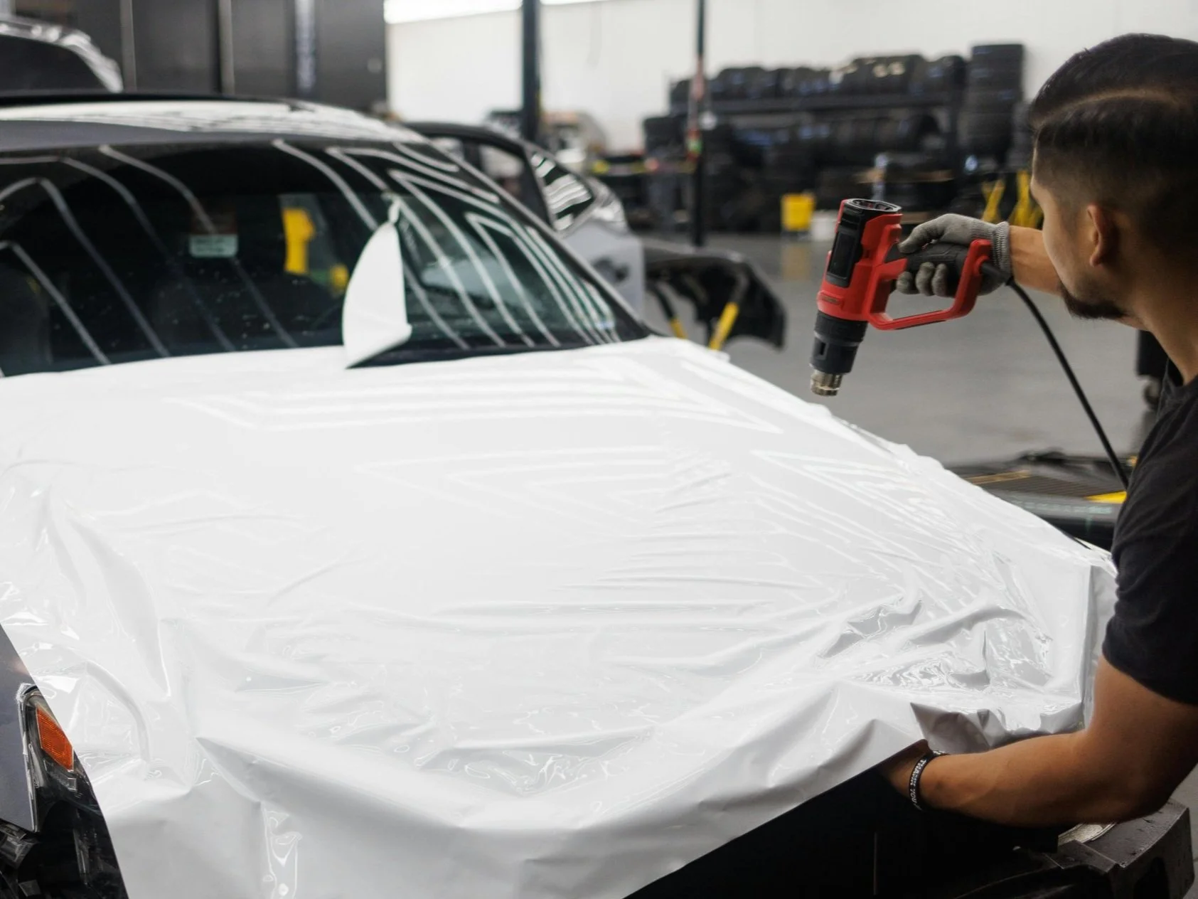 Student learning professional window tint application using a heat gun during hands-on training at Qualls Quality Tints