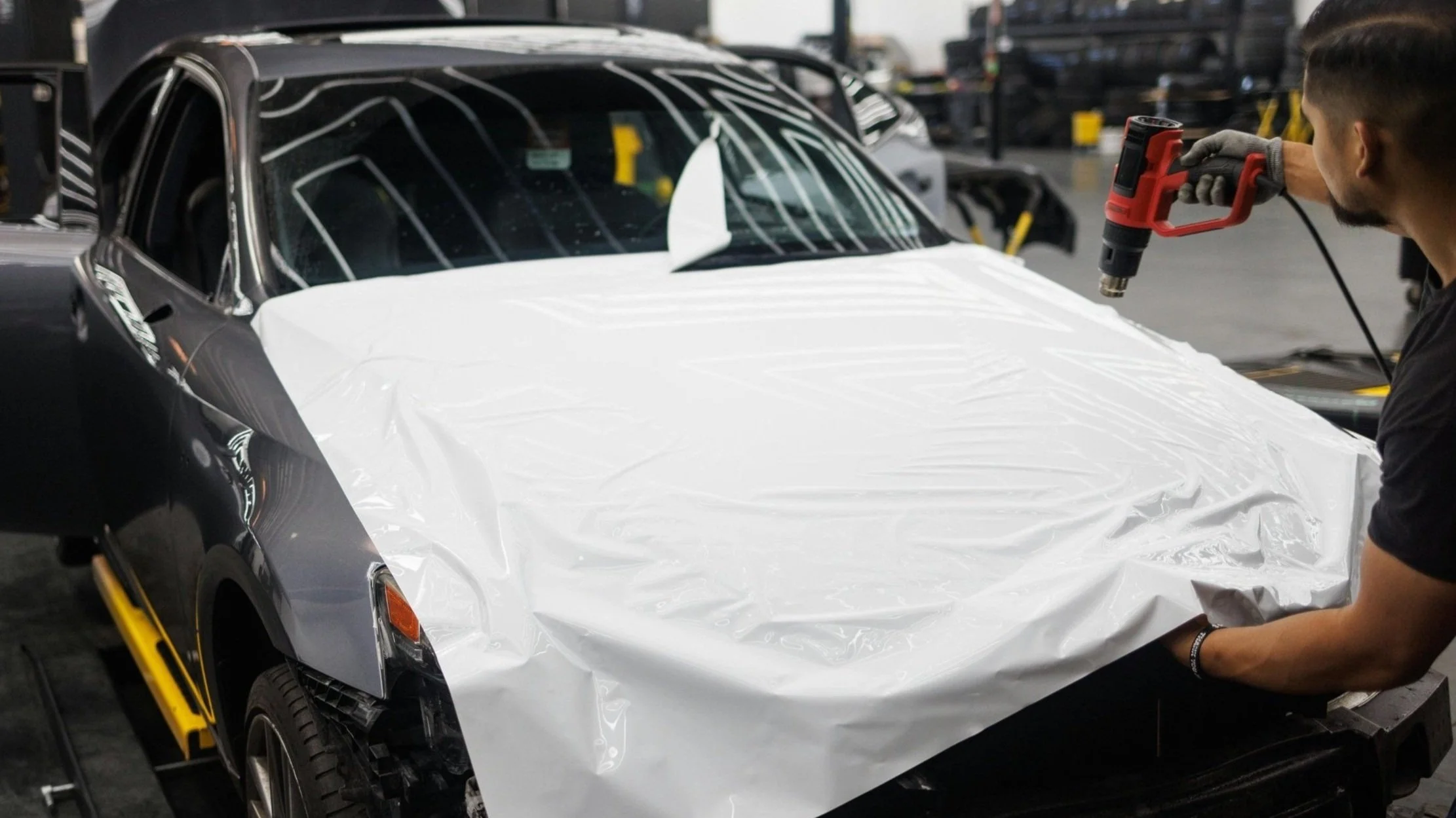 Student learning professional window tint application using a heat gun during hands-on training at Qualls Quality Tints