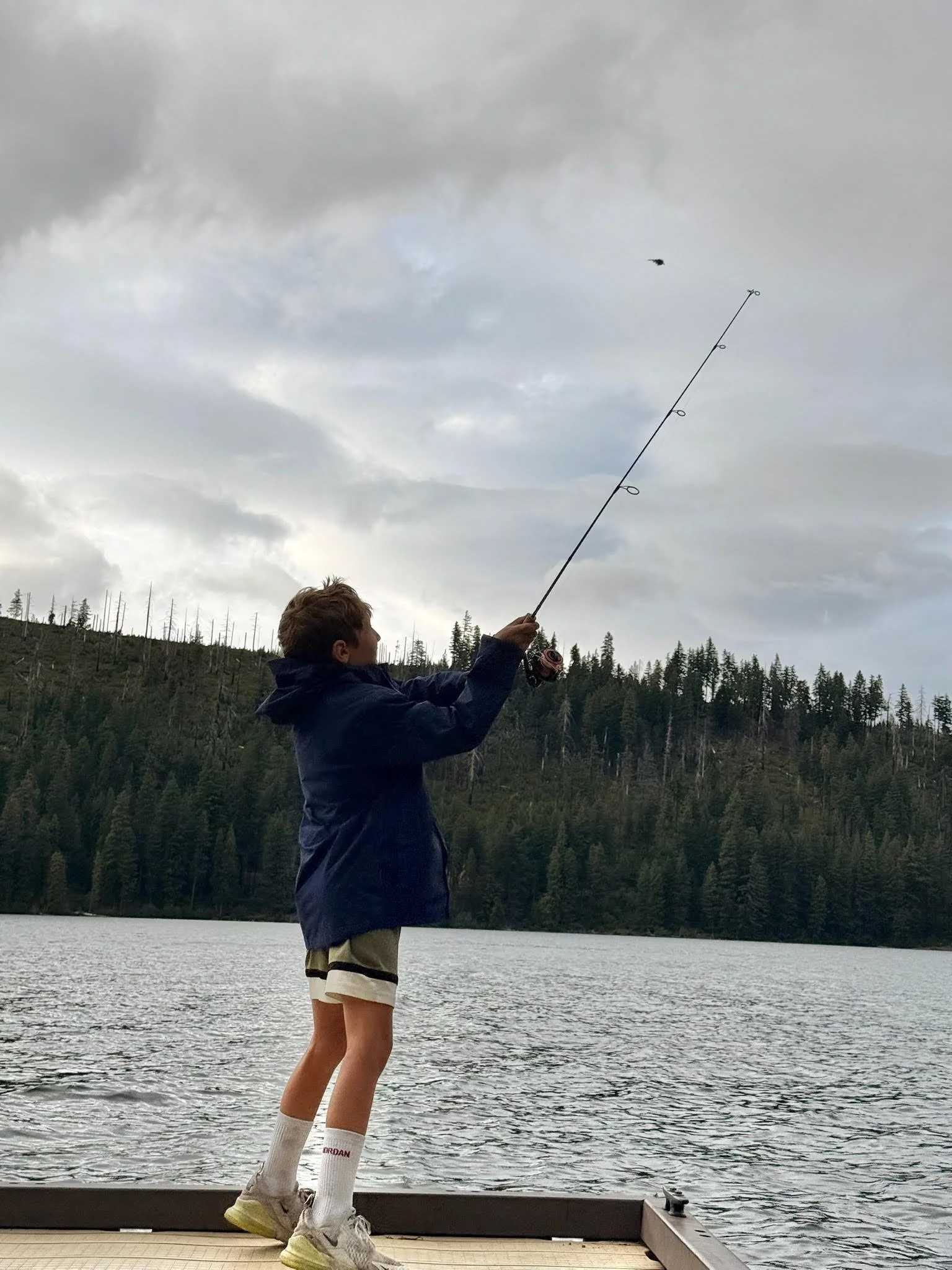 Kid casting a fishing line from the dock at Suttle Lake Campground in Sisters Oregon, fishing on Suttle Lake in the Deschutes National Forest of Central Oregon