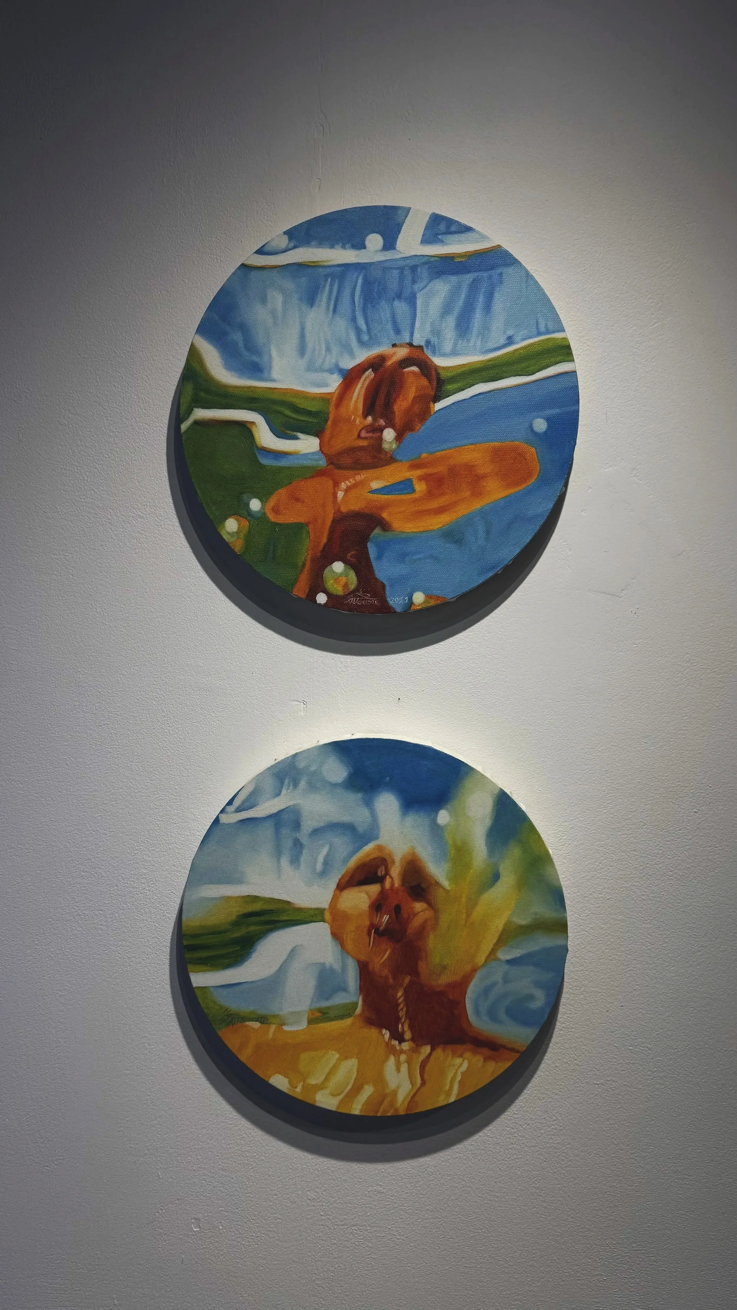 Deux tableaux ronds peint à la main, représentant des animaux dans un style coloré et abstrait, accrochés à un mur blanc.