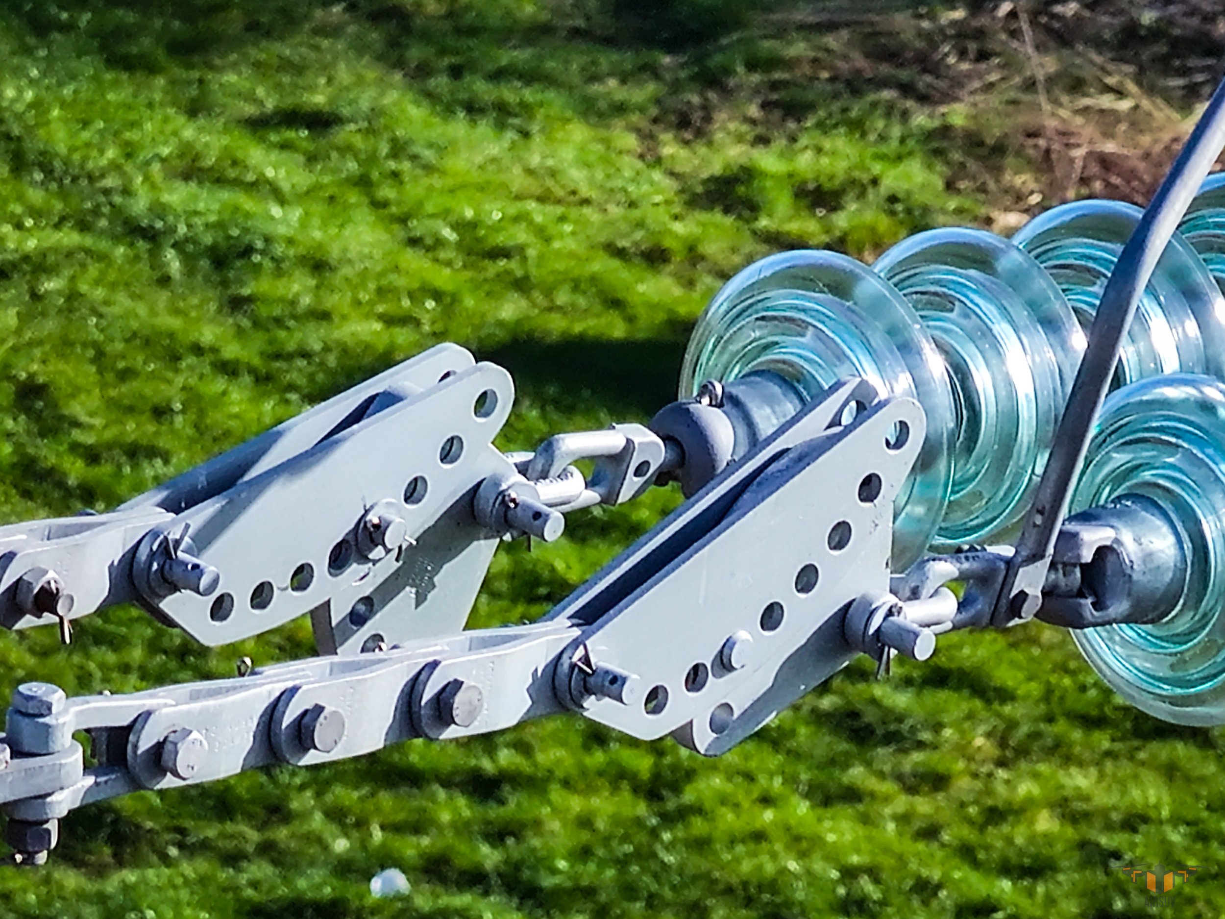 Close-up of a mechanical device with glass discs and metal components on a grassy background.