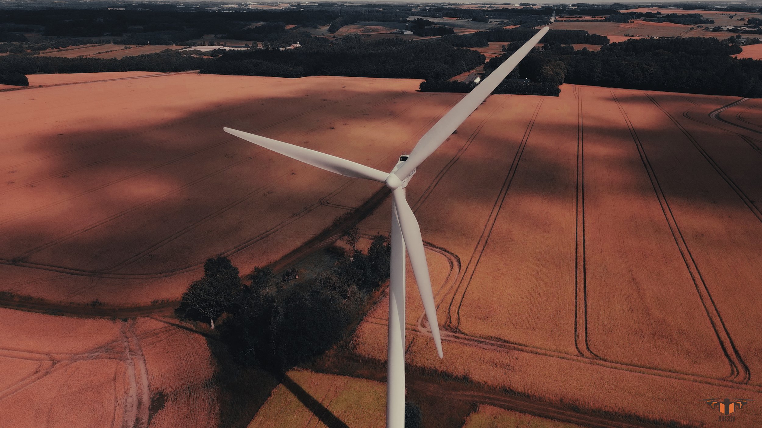Aerial drone overview of wind turbine showing full rotor assembly, nacelle and tower above agricultural land — Airsuv ARC-structured wind turbine inspection data capture