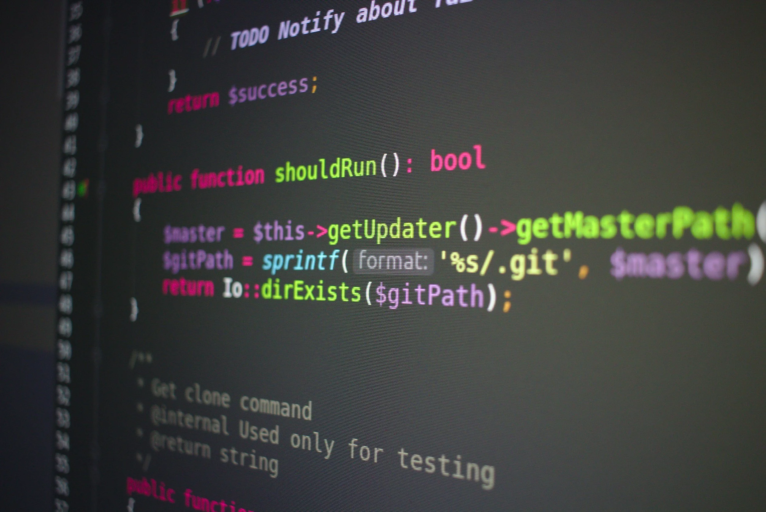 Close-up of a computer screen displaying colorful programming code in a text editor, with visible syntax highlighting in pink, green, blue, and white.