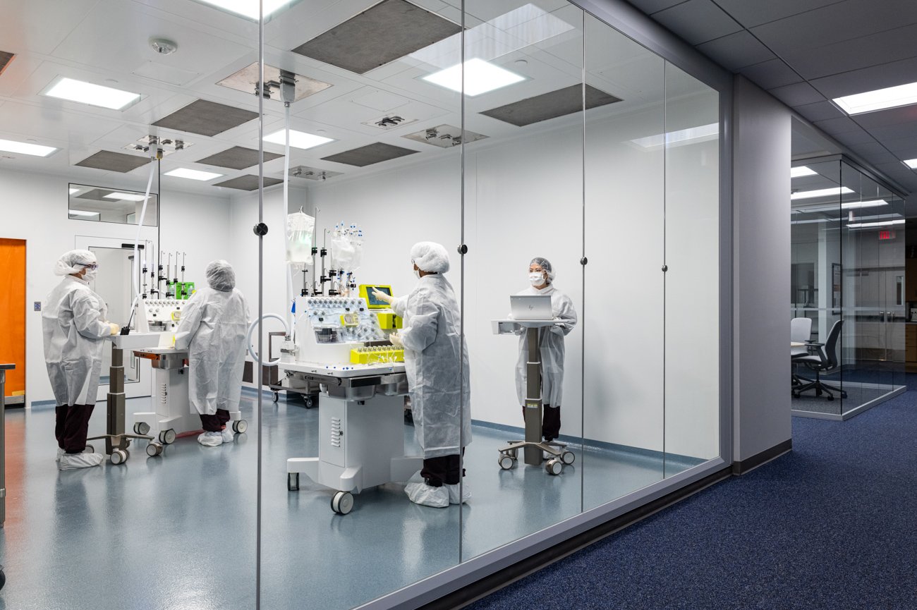 Medical professionals working in a sterile laboratory, wearing white protective suits and masks, with advanced medical equipment and monitors in a clean room.