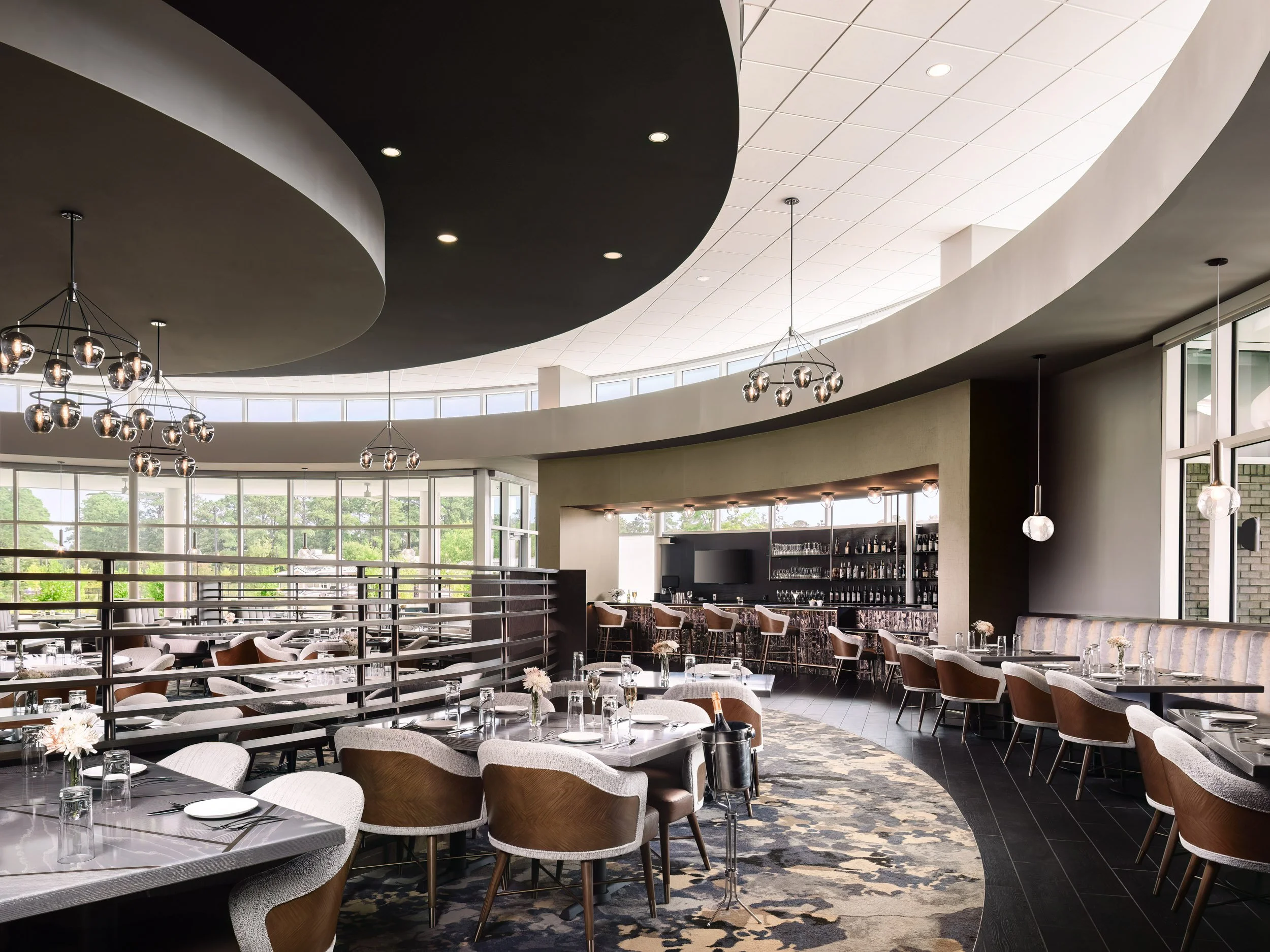 Elegant modern restaurant interior with large windows, contemporary lighting fixtures, and a bar area.