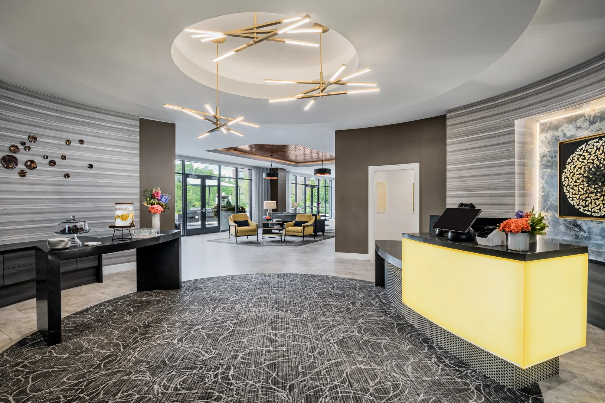 Modern hotel lobby with seating area, reception desk, and contemporary lighting fixtures.